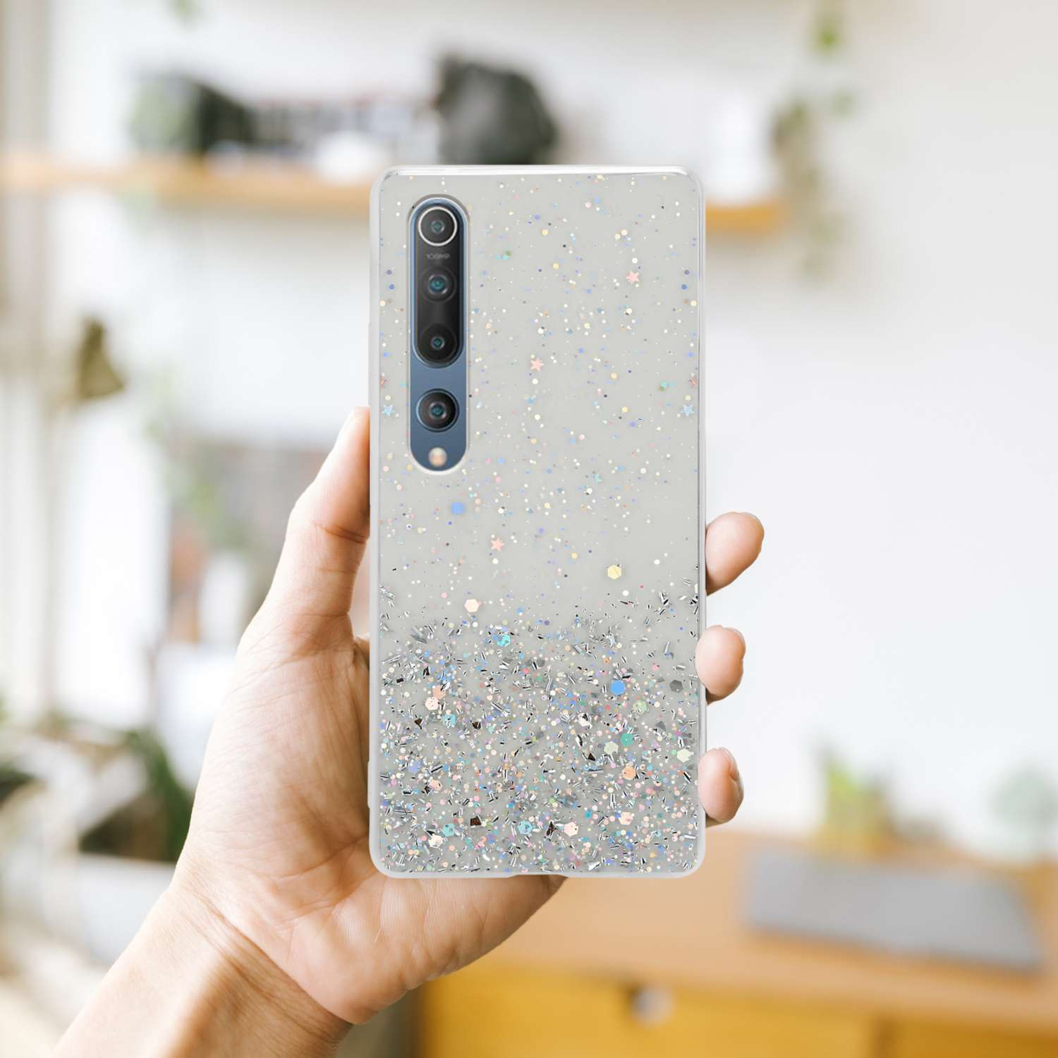 Una mano che tiene una custodia per telefono con glitter. La custodia è trasparente con glitter.