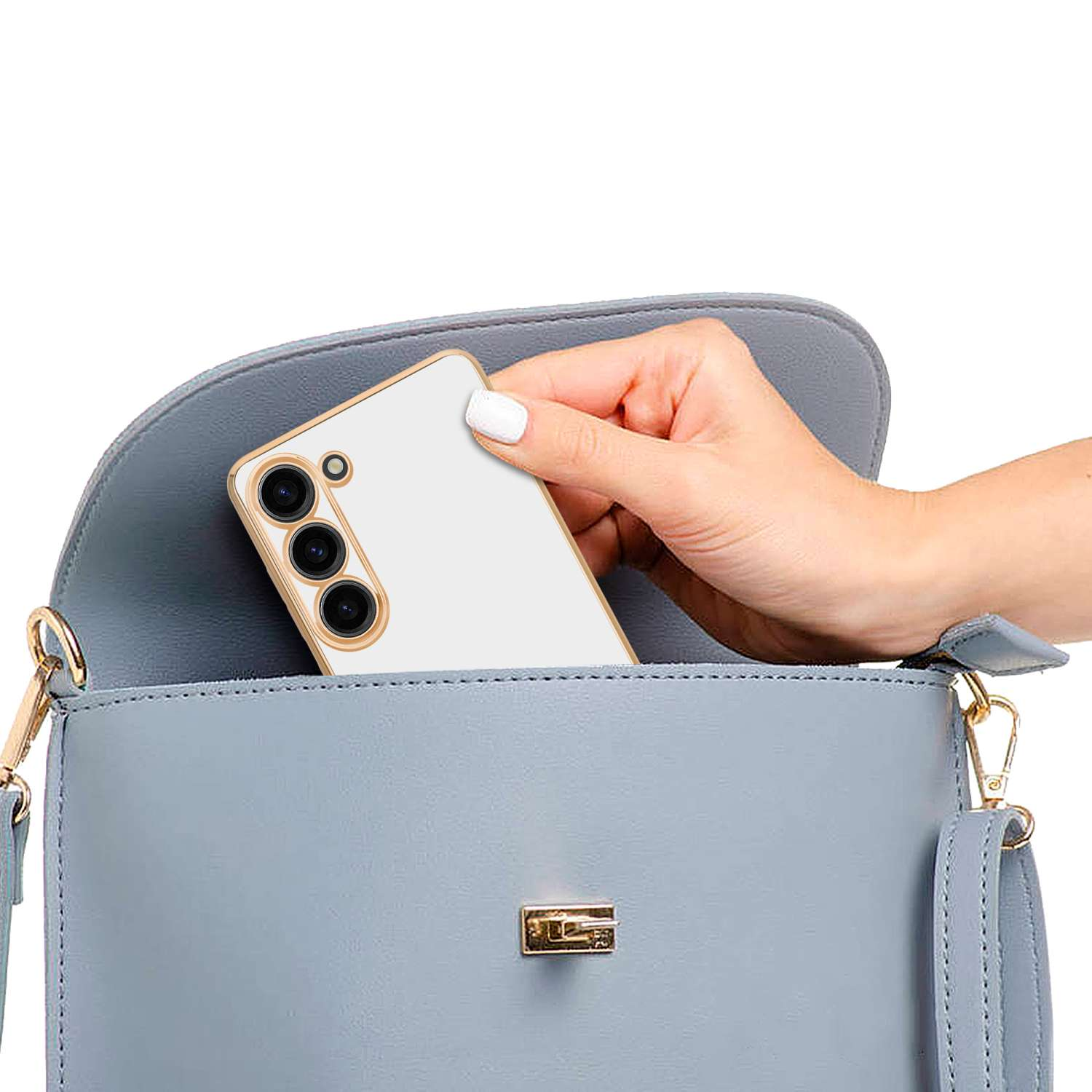 Una mano che tiene un telefono bianco con cornice dorata all'interno di una borsa blu. Il telefono ha tre obiettivi.