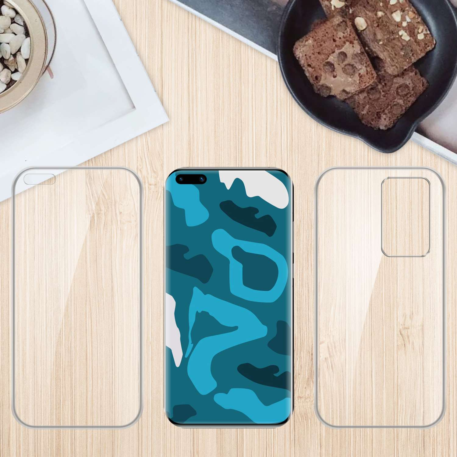 Custodie per telefono su tavolo di legno con cibo e decorazioni. Una custodia ha un design mimetico blu.