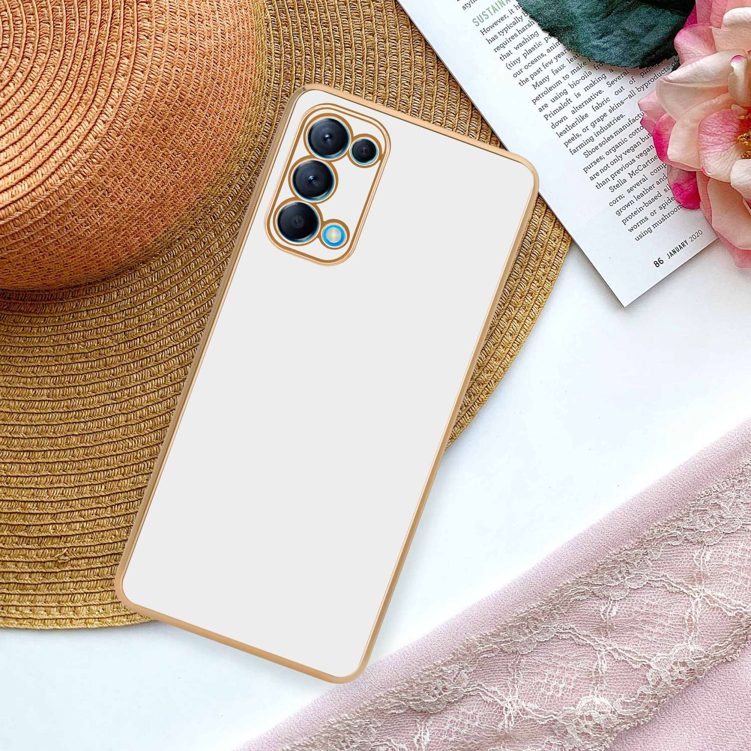 Una custodia per telefono bianca con cornice dorata, con una configurazione della fotocamera, posizionata su una rivista.