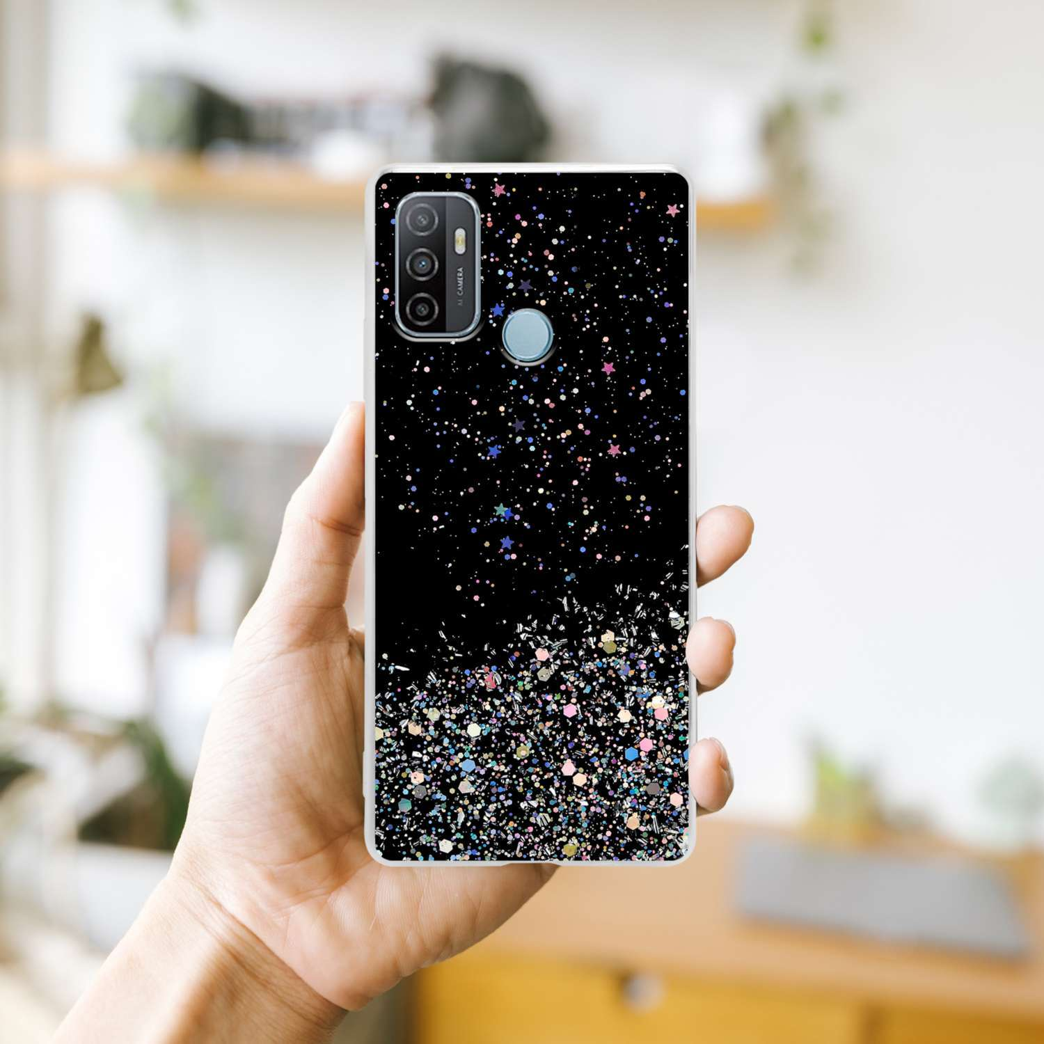 Mano che tiene telefono con custodia nera, design glitterato in basso.
