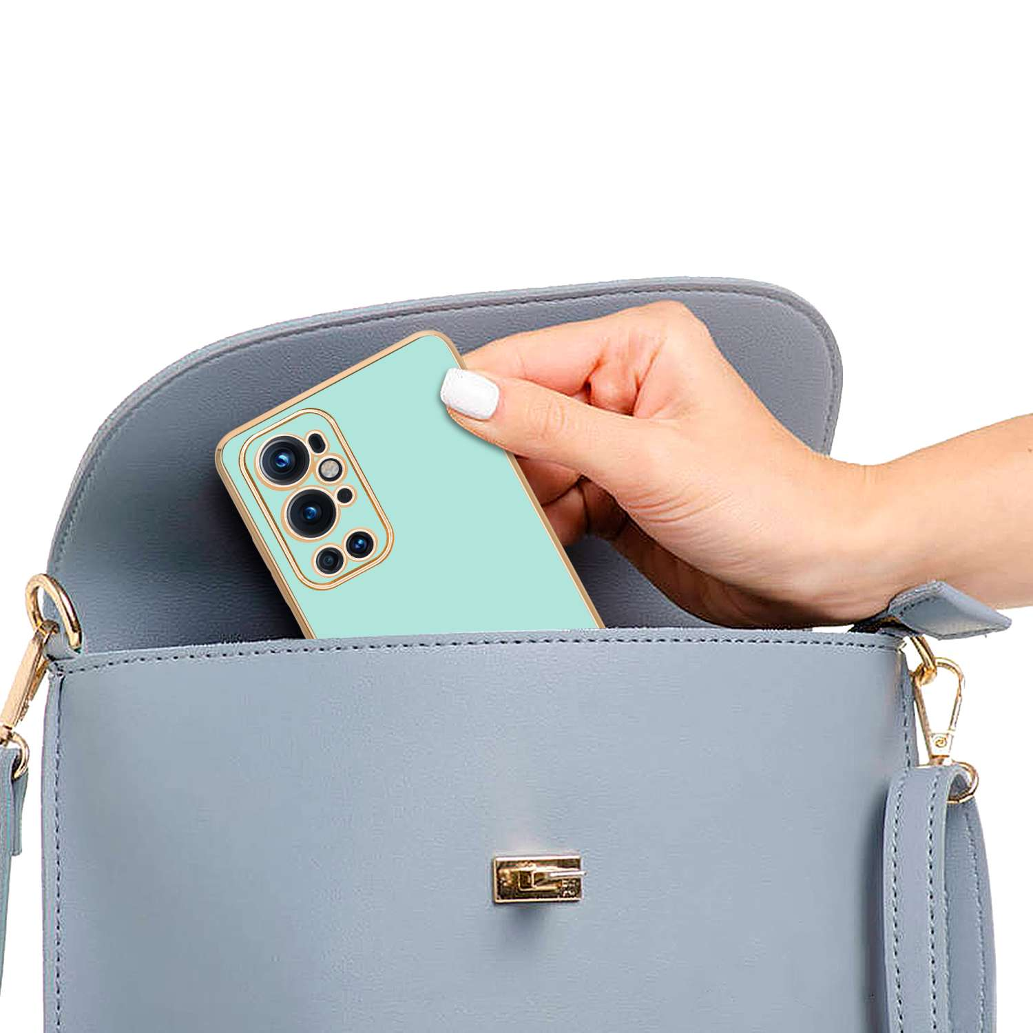 Mano che mette un telefono verde menta con custodia in una borsetta grigia.