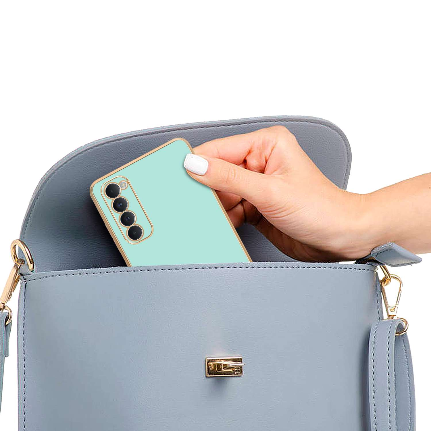 Mano che mette un telefono verde menta con custodia in una borsetta azzurra.
