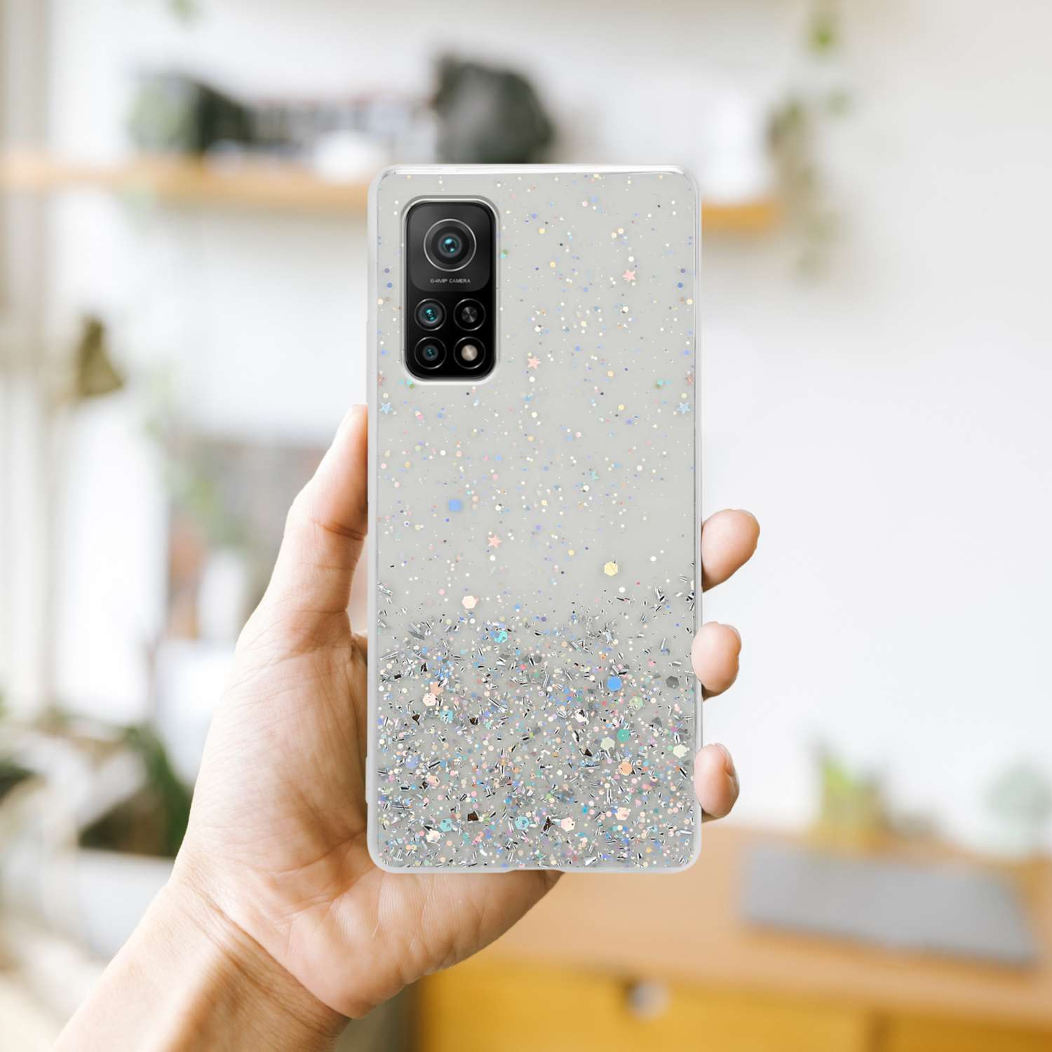 Una mano che tiene un telefono con una custodia glitterata. La custodia ha un design scintillante.
