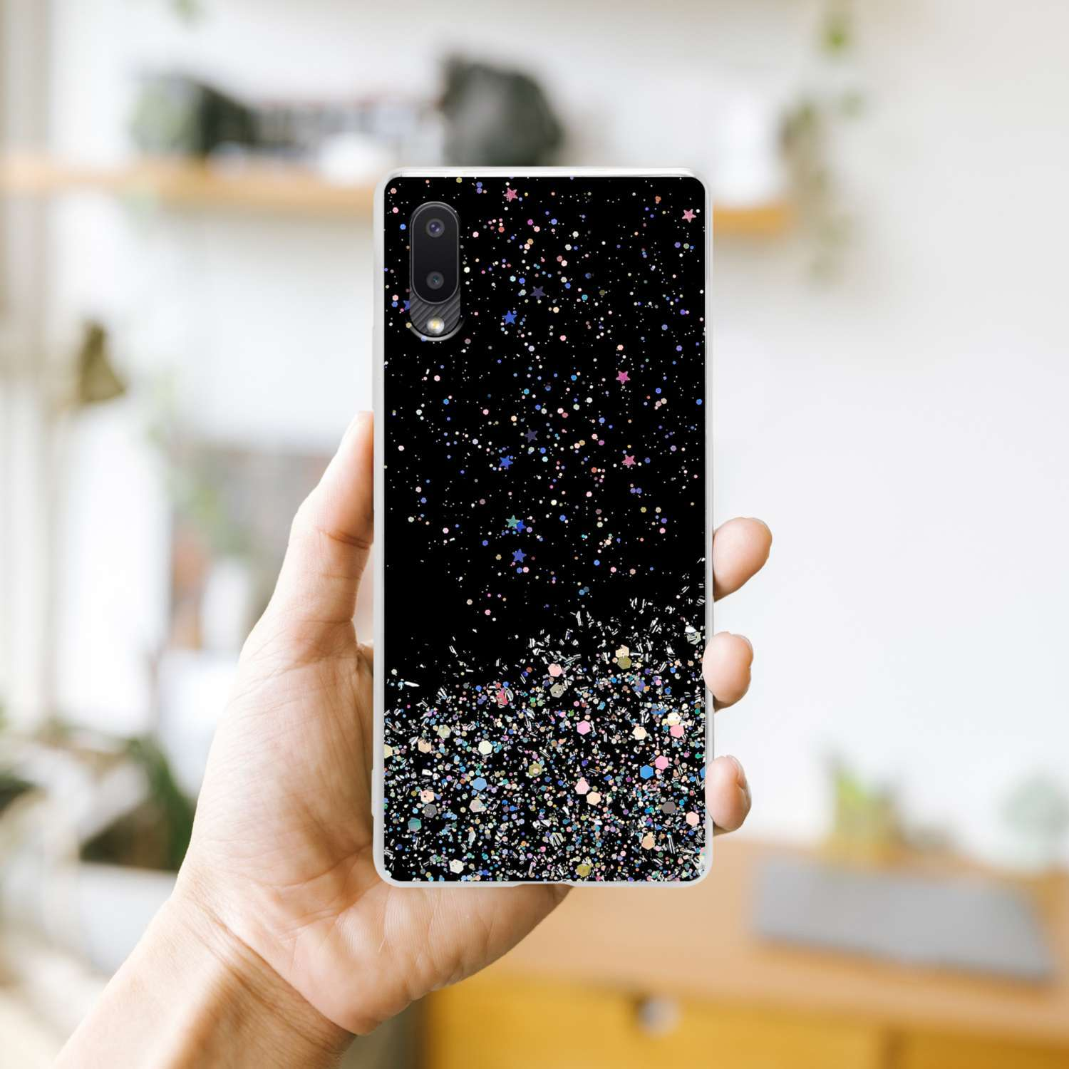 Una mano che tiene una custodia per telefono con glitter e un retro decorato.