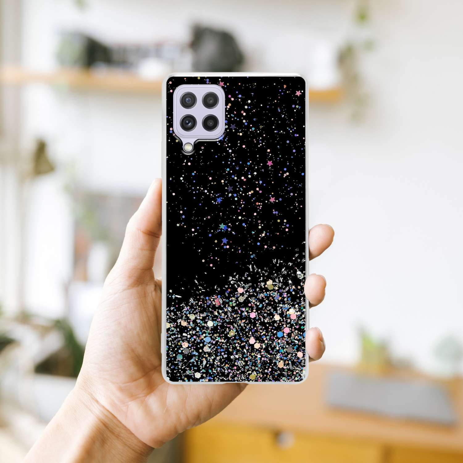 Una mano tiene una custodia per telefono con sfondo nero coperto di brillantini. La custodia ha una fotocamera.