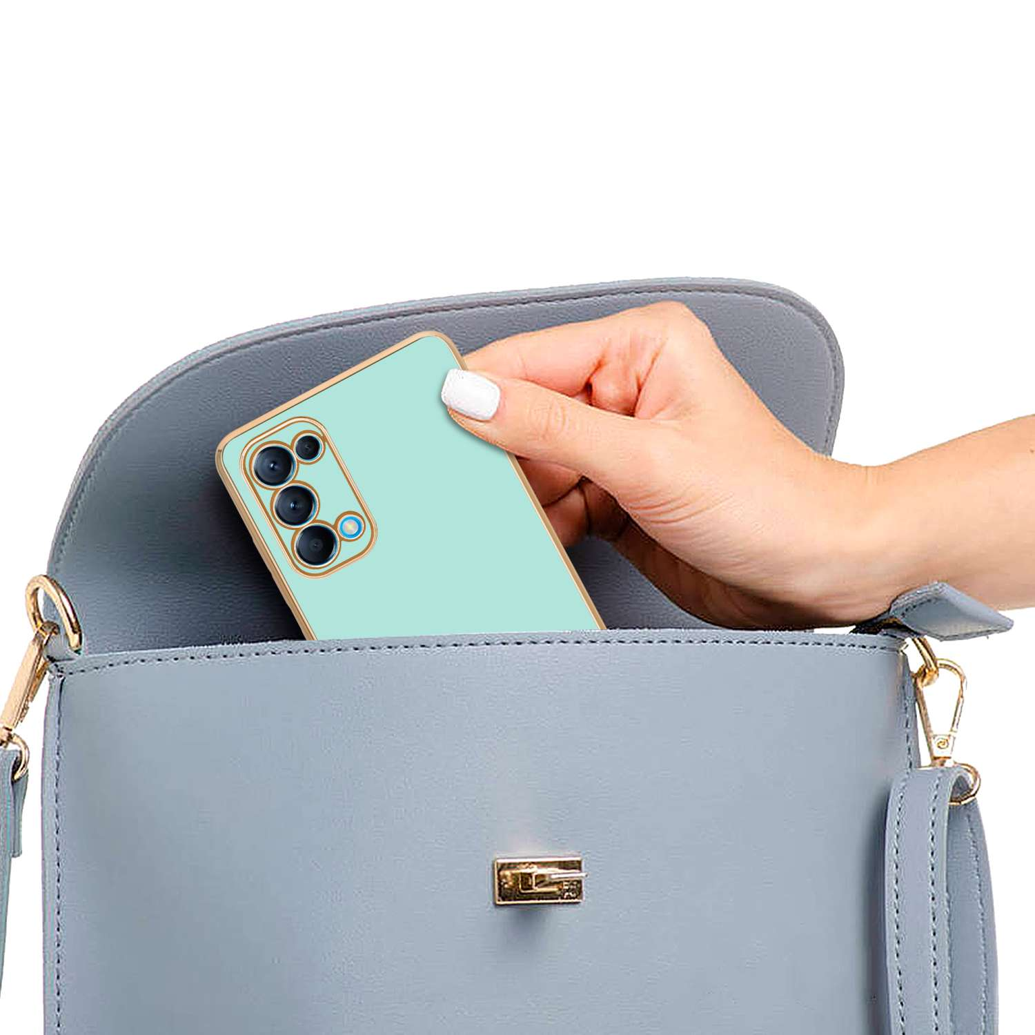 Mano che mette un telefono verde menta in una borsa azzurra. Sfondo bianco.
