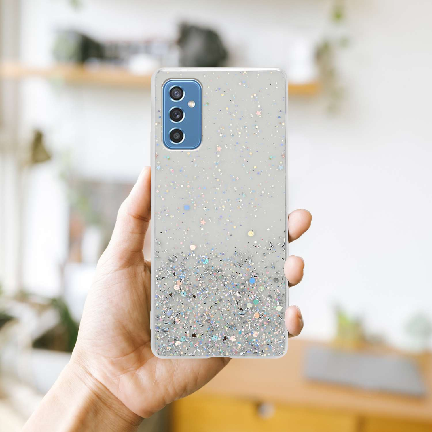 Una mano che tiene una custodia per telefono con glitter. La custodia ha un design glitterato argento.