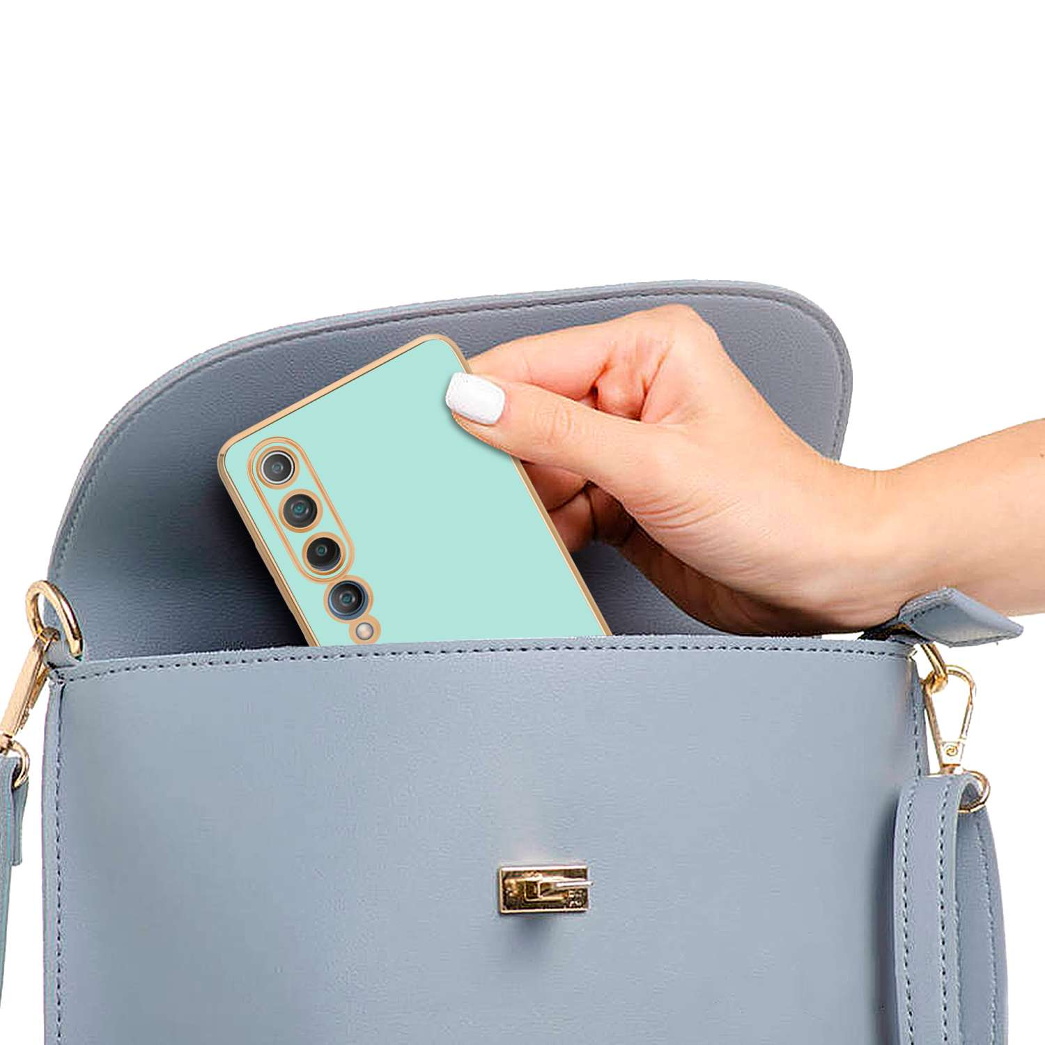 Mano che mette un telefono verde menta in una borsa azzurra. Borsa su sfondo bianco.