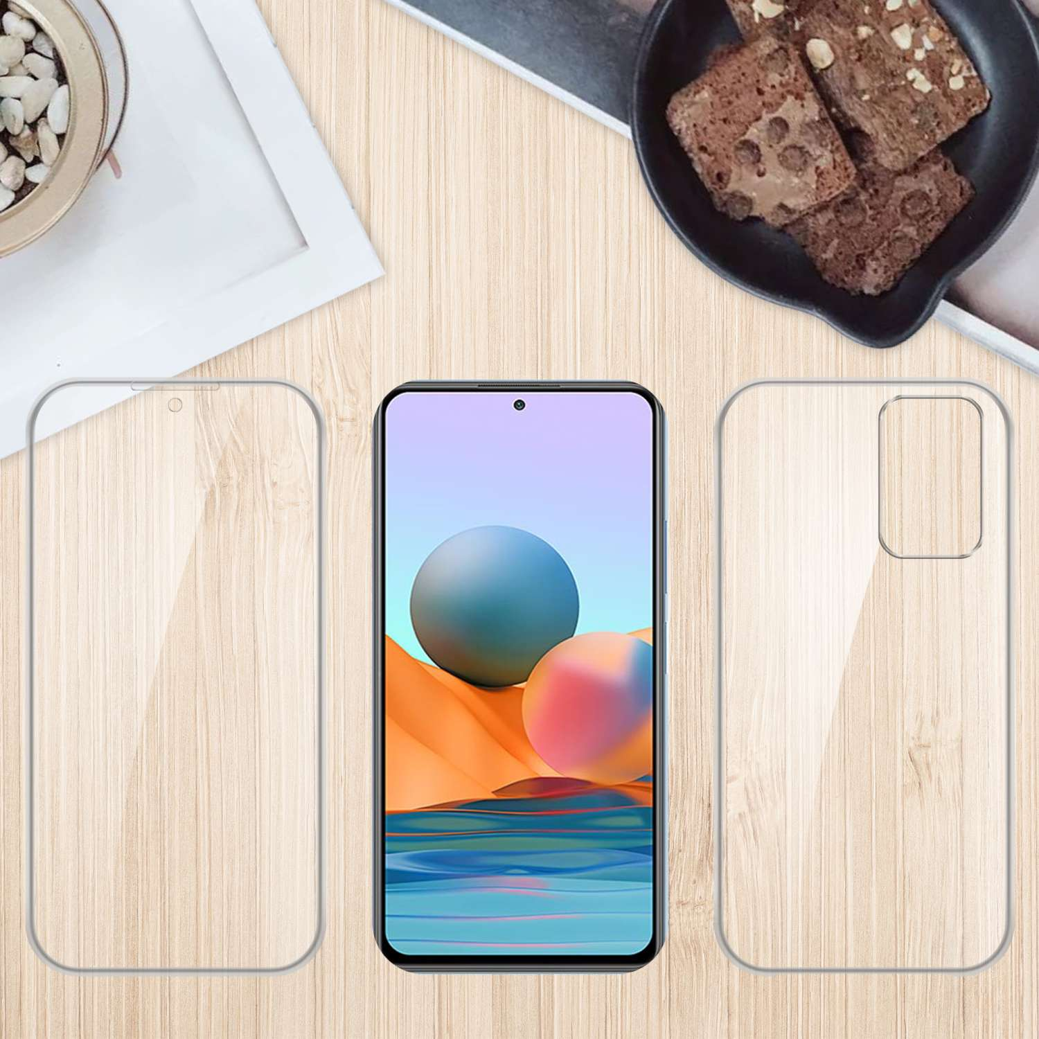 Un teléfono y dos protectores de pantalla transparentes están sobre una mesa de madera con comida al fondo.