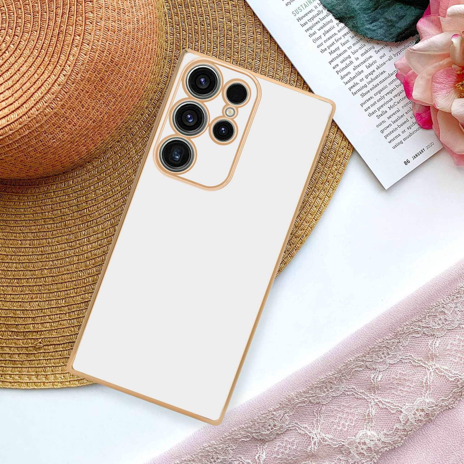 Custodia per telefono su rivista con sciarpa rosa e fiore. La custodia è beige e oro.