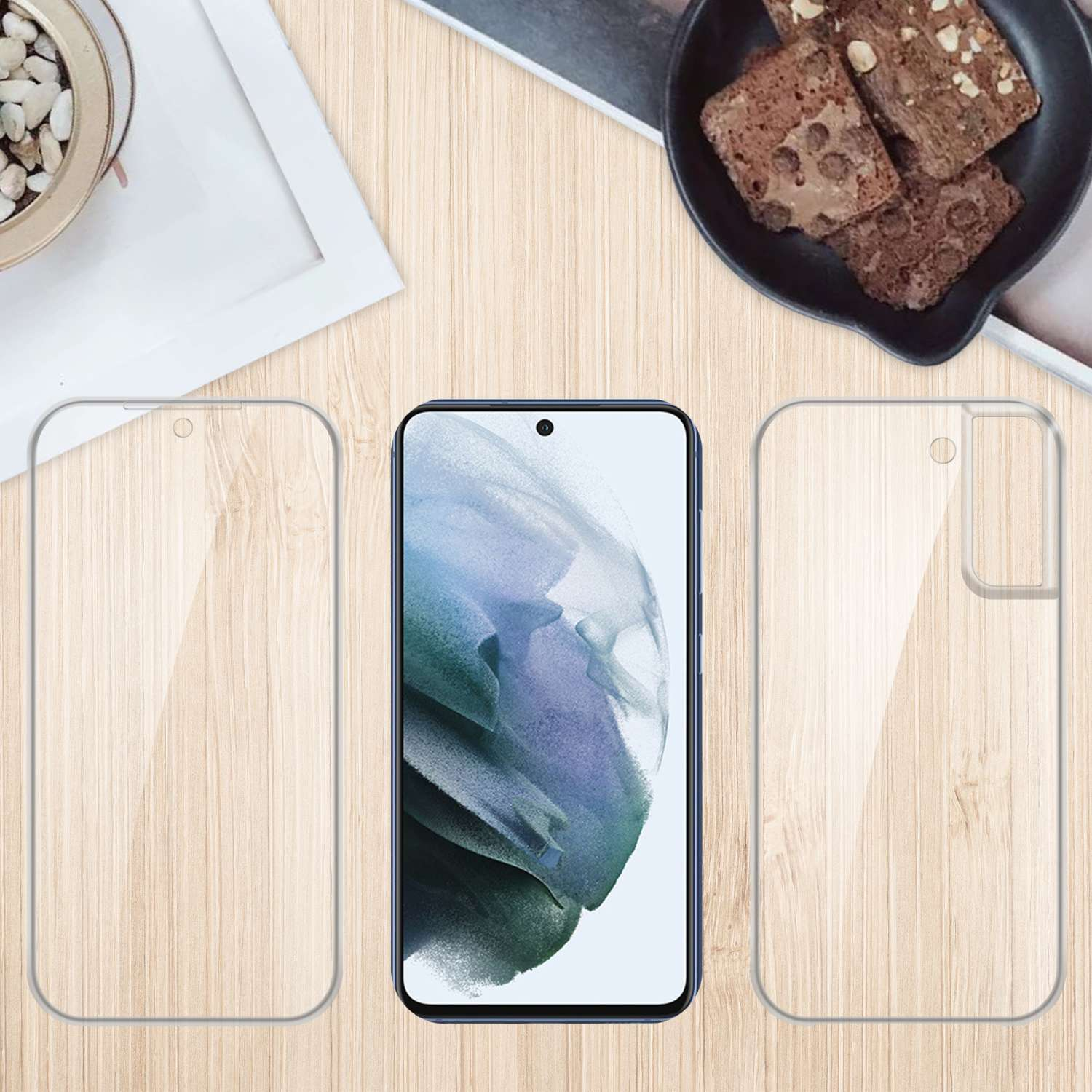 Telefono, protezione schermo e custodia su tavolo di legno, brownies e pianta sullo sfondo.