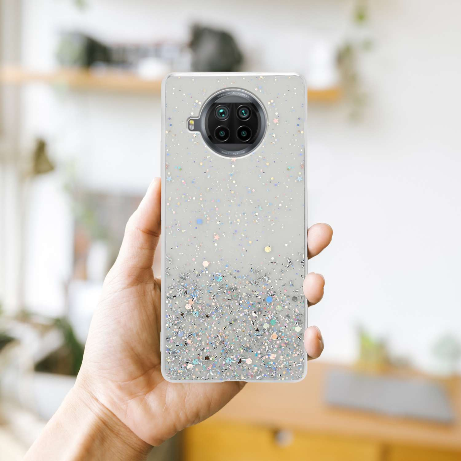 Hand hält eine Handyhülle mit Glitzer und Sternen. Das Telefon hat mehrere Kameras.