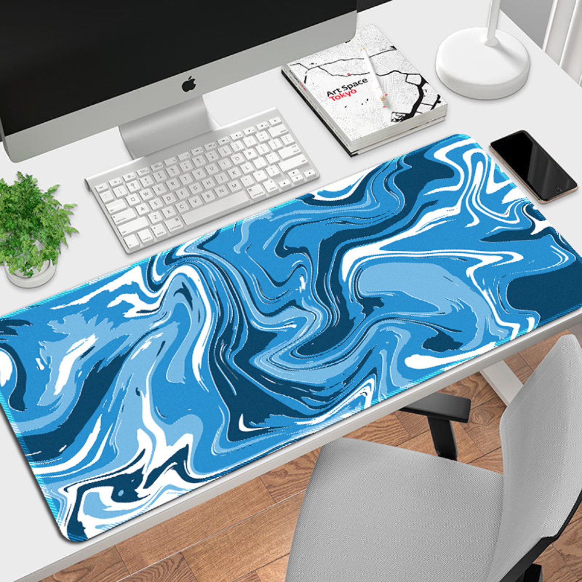 Blau gemustertes Mauspapier auf einem Schreibtisch mit Computer und Zubehör.