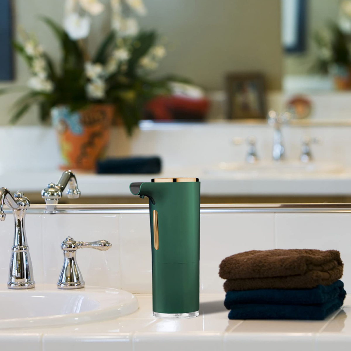 Waschbecken mit grünem Seifenspender, Handtüchern und Spiegel im Hintergrund.
