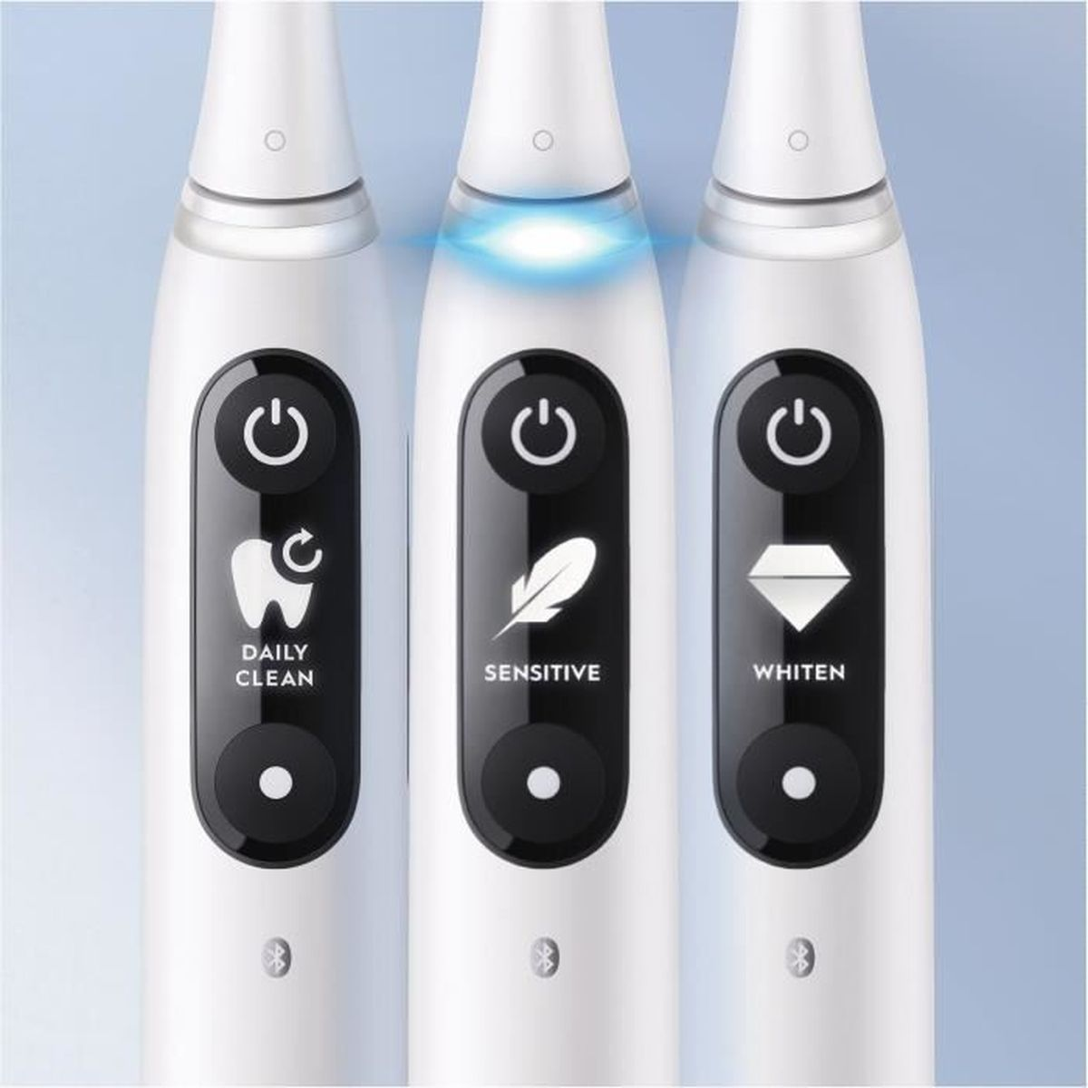 Primer plano de tres cepillos de dientes eléctricos blancos. Cada uno con iconos de modo: Limpieza diaria, Sensible y Blanqueamiento.