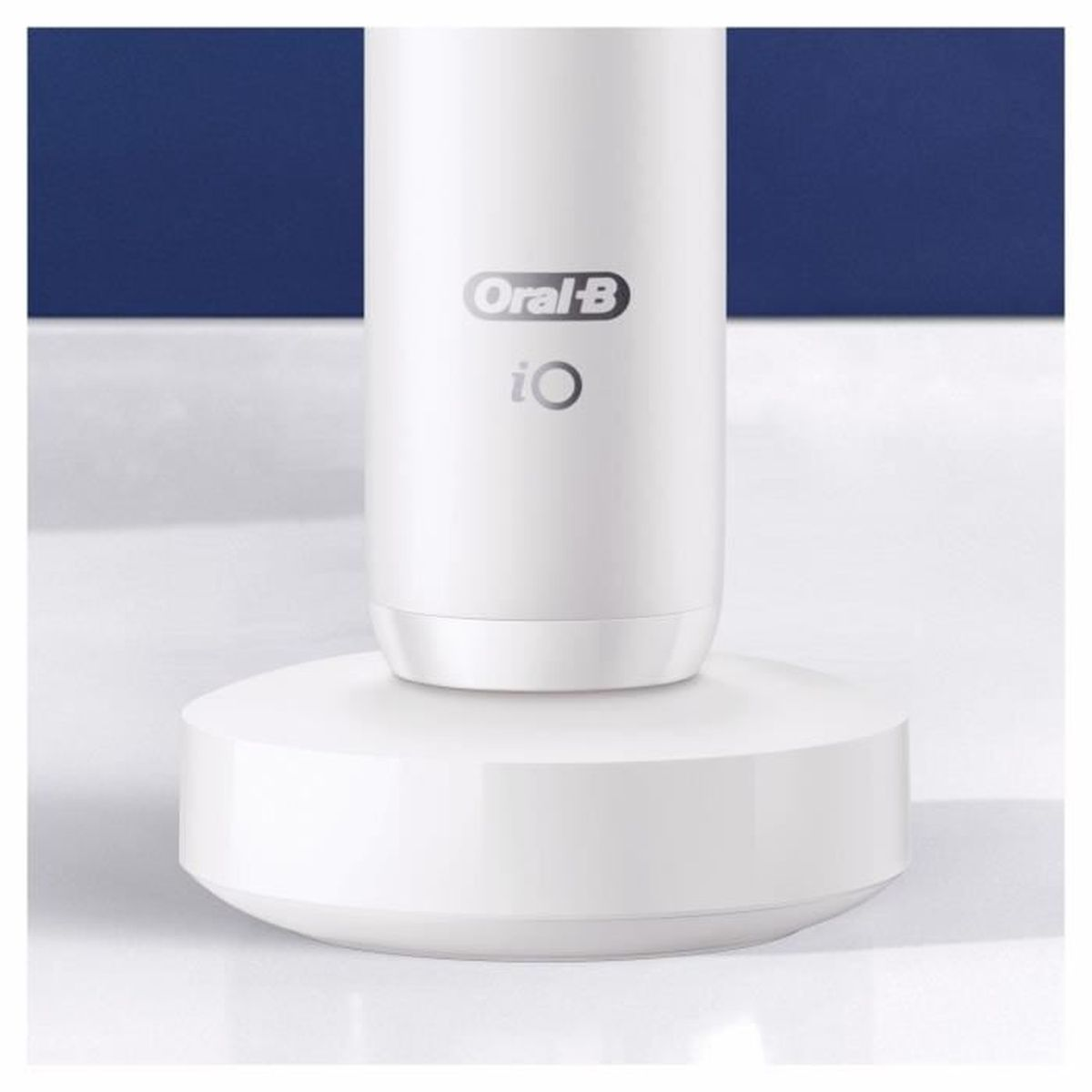 Cepillo de dientes eléctrico blanco, sobre una base blanca. Fondo azul detrás.
