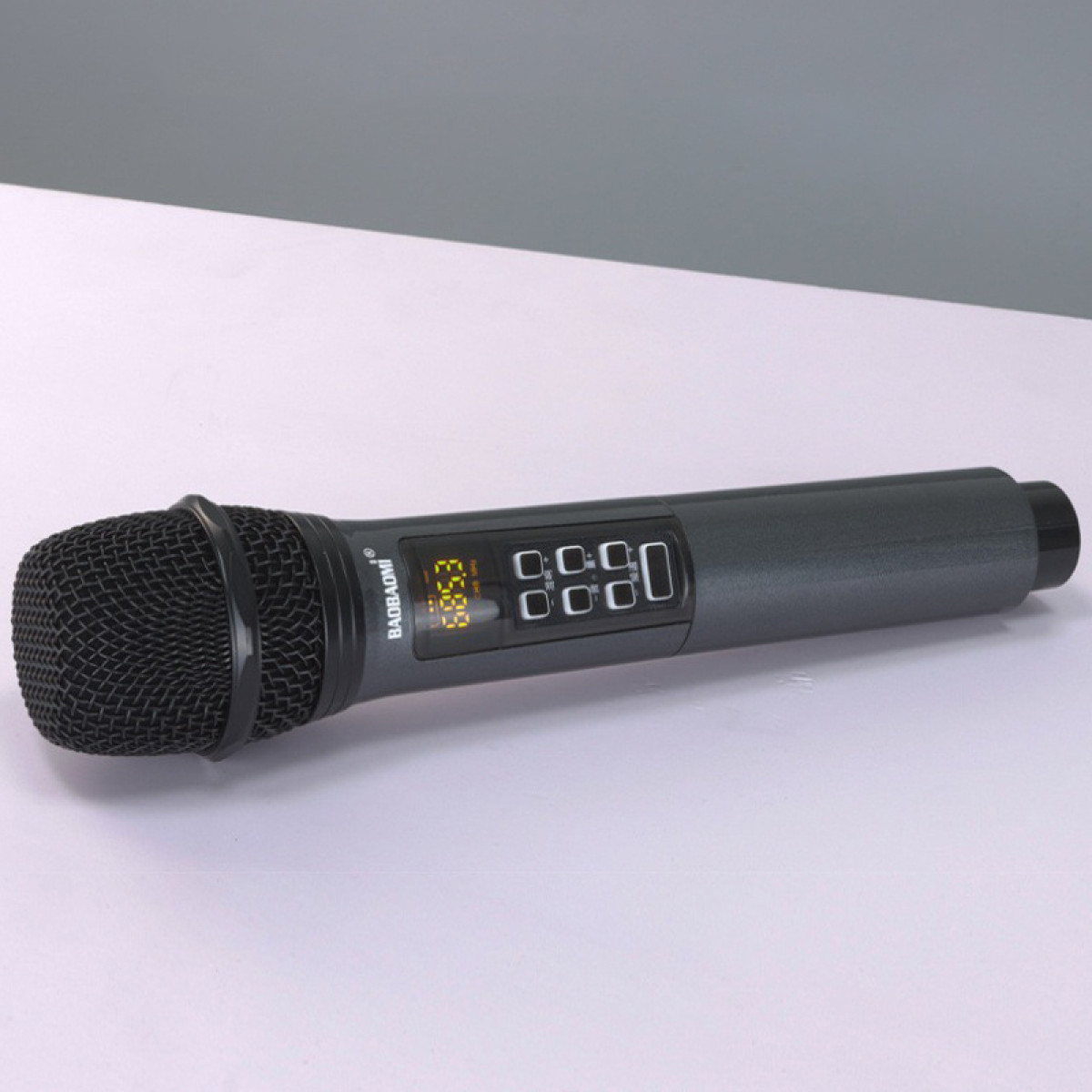 Czarny mikrofon z wyświetlaczem i przyciskami. Szary korpus, czarna siatkowa głowica. Białe tło, ujęcie pod kątem.