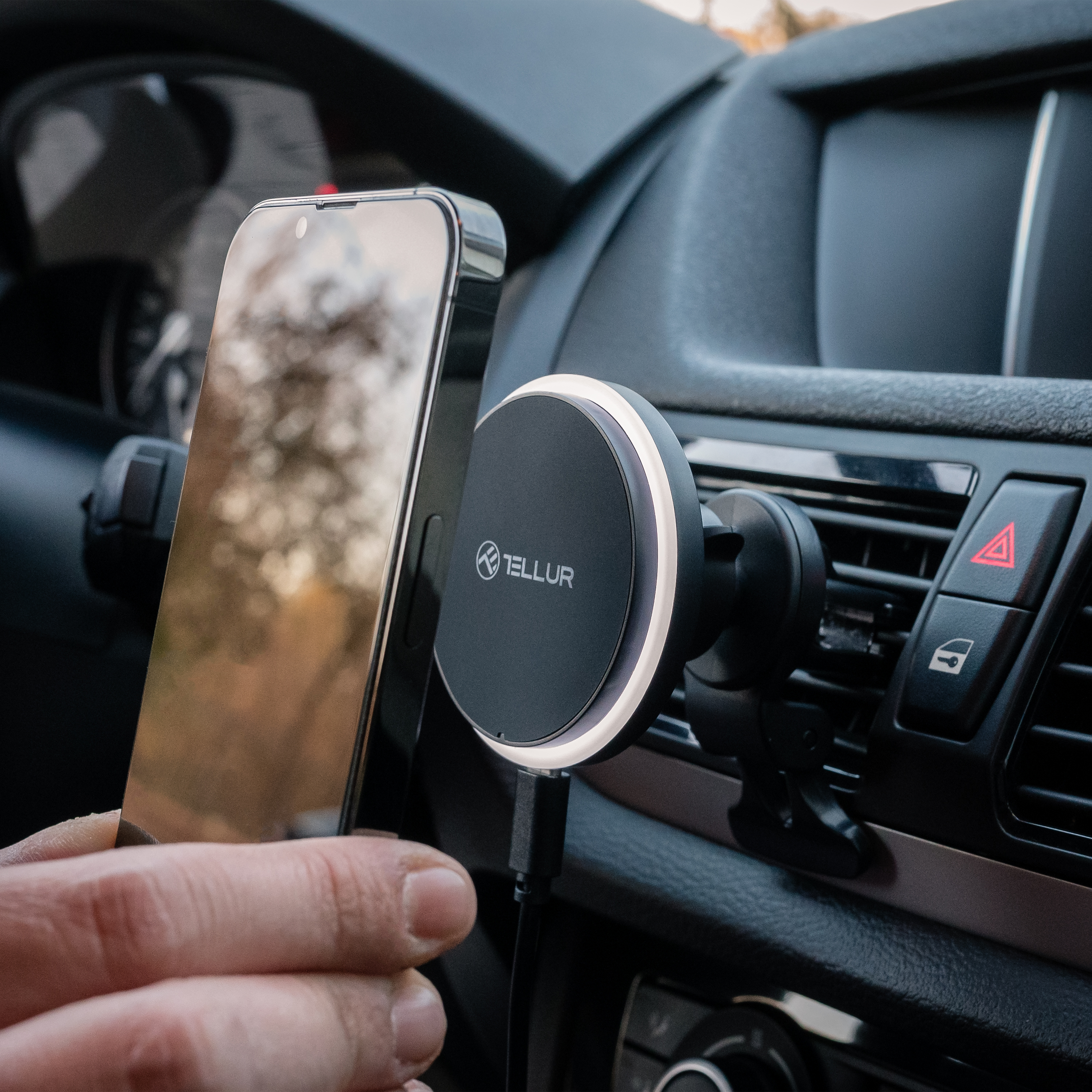 Telefon jest przymocowany do uchwytu samochodowego. Ładowarka jest podłączona do telefonu.