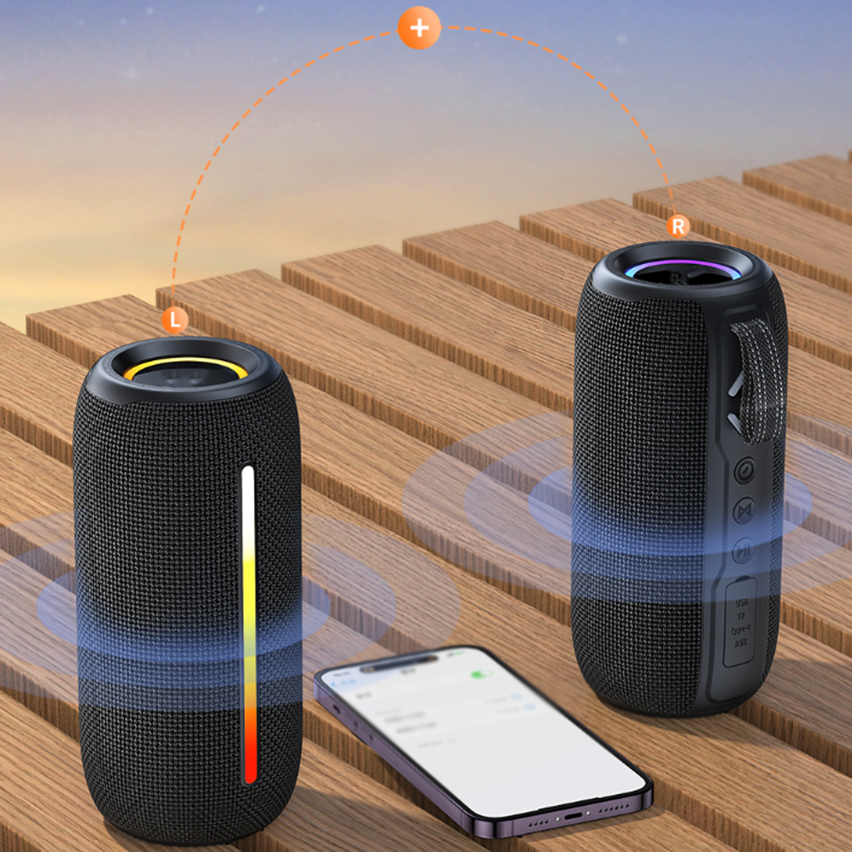 Zwei schwarze Lautsprecher mit Telefon, auf Holzoberfläche. Orange-weißes Licht.