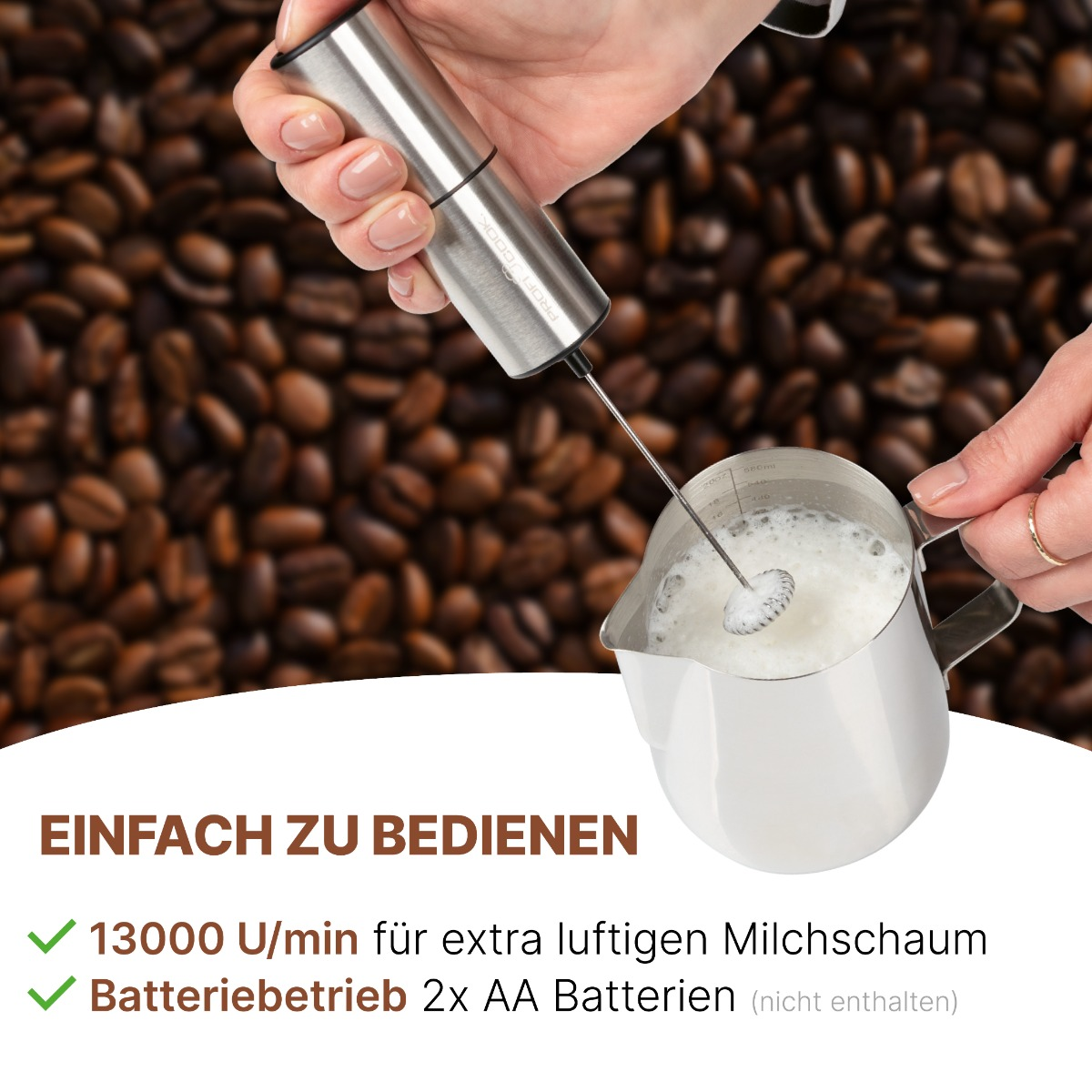 Osoba spienia mleko srebrnym spieniaczem. Ziarna kawy w tle, używany jest metalowy dzbanek.