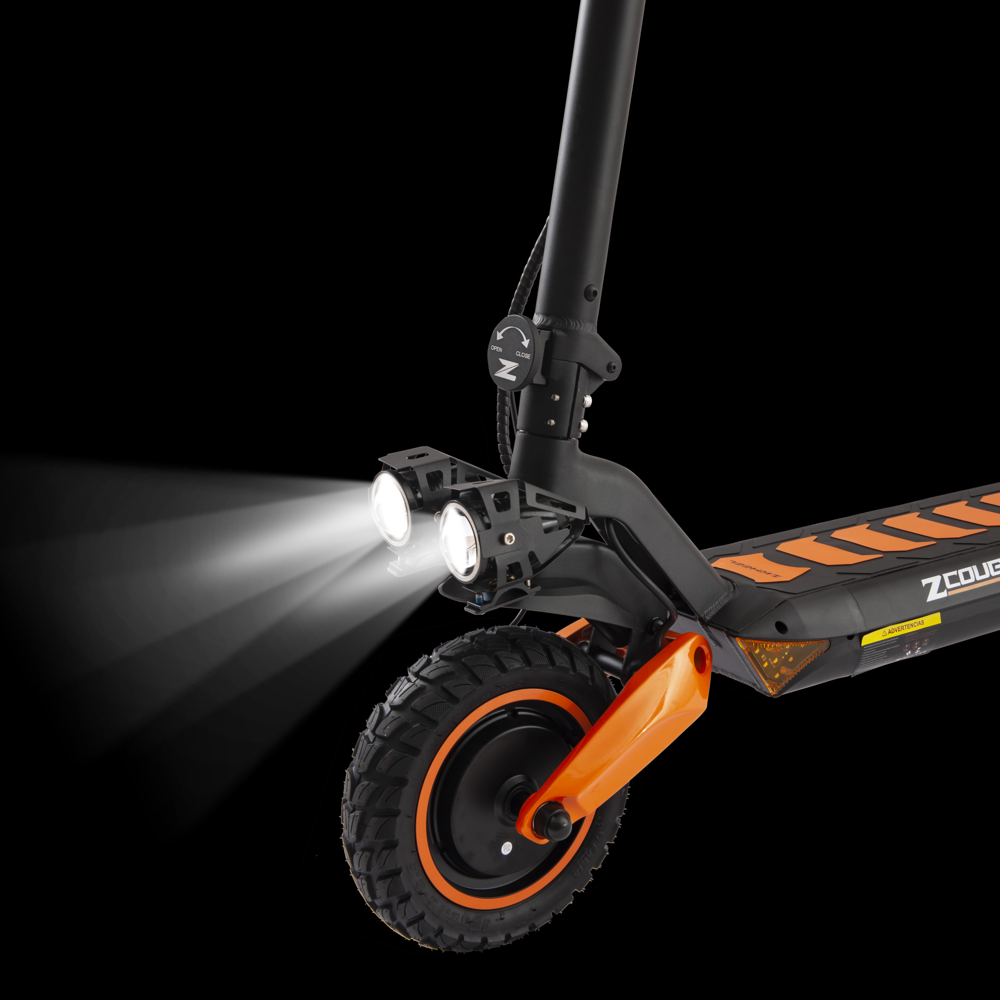Patinete eléctrico con faros brillantes. El patinete es negro y naranja, sobre fondo negro.