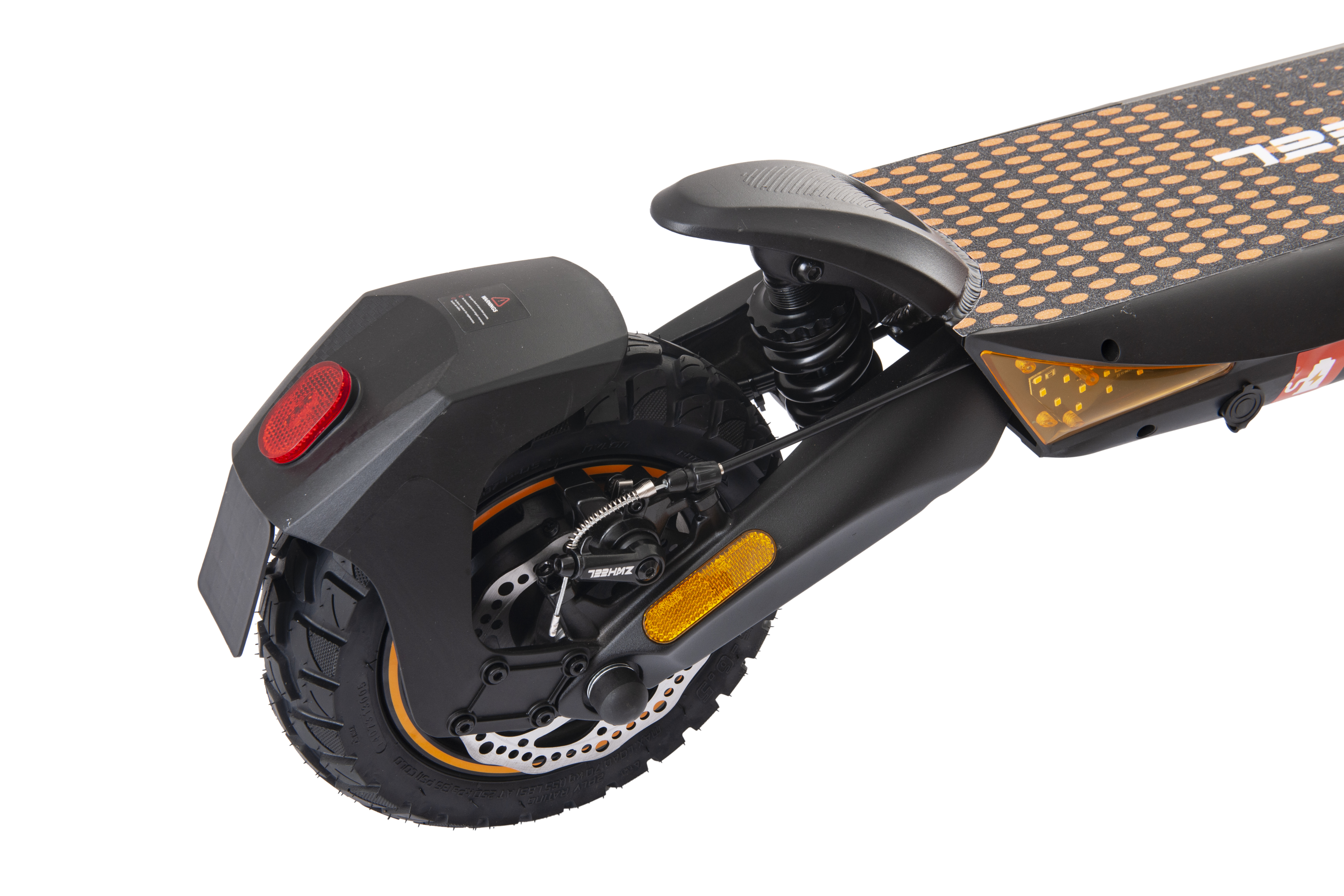 Primer plano de la rueda trasera y suspensión de un patinete eléctrico negro y naranja. Fondo negro.