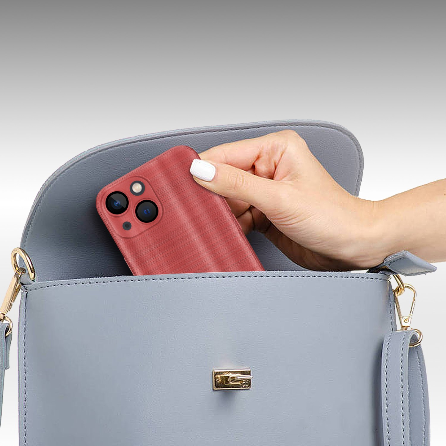 Hand legt ein rotes Telefon in eine hellblaue Handtasche. Handtasche hat einen goldenen Verschluss.