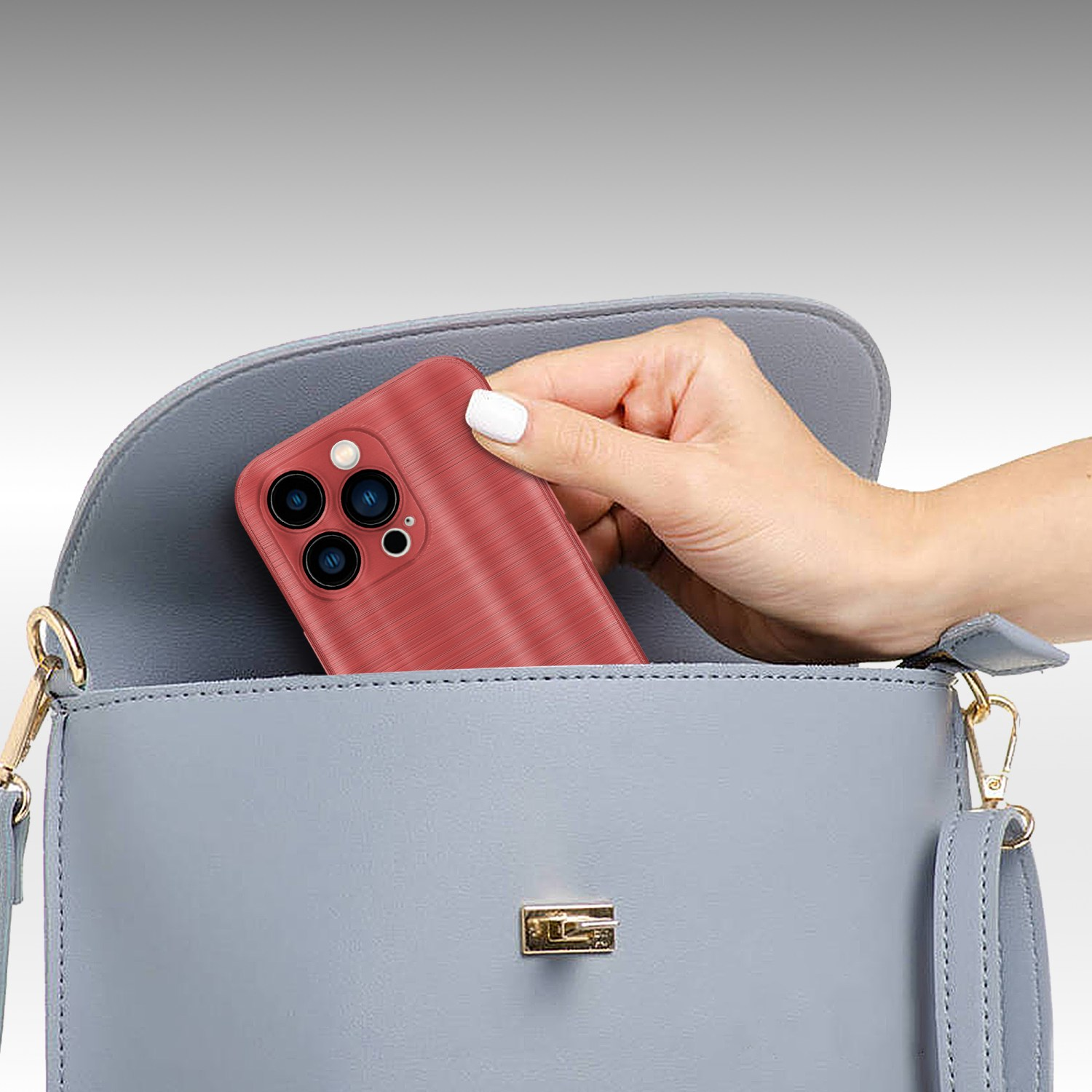 Eine Hand legt eine rote Handyhülle in eine blaue Handtasche. Die Handtasche ist geöffnet.