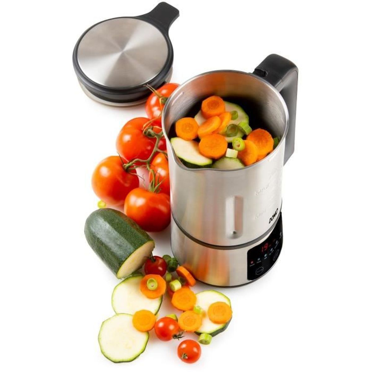Een zilveren keukenmachine met groenten erin en eromheen, waaronder tomaten en courgetteschijfjes.