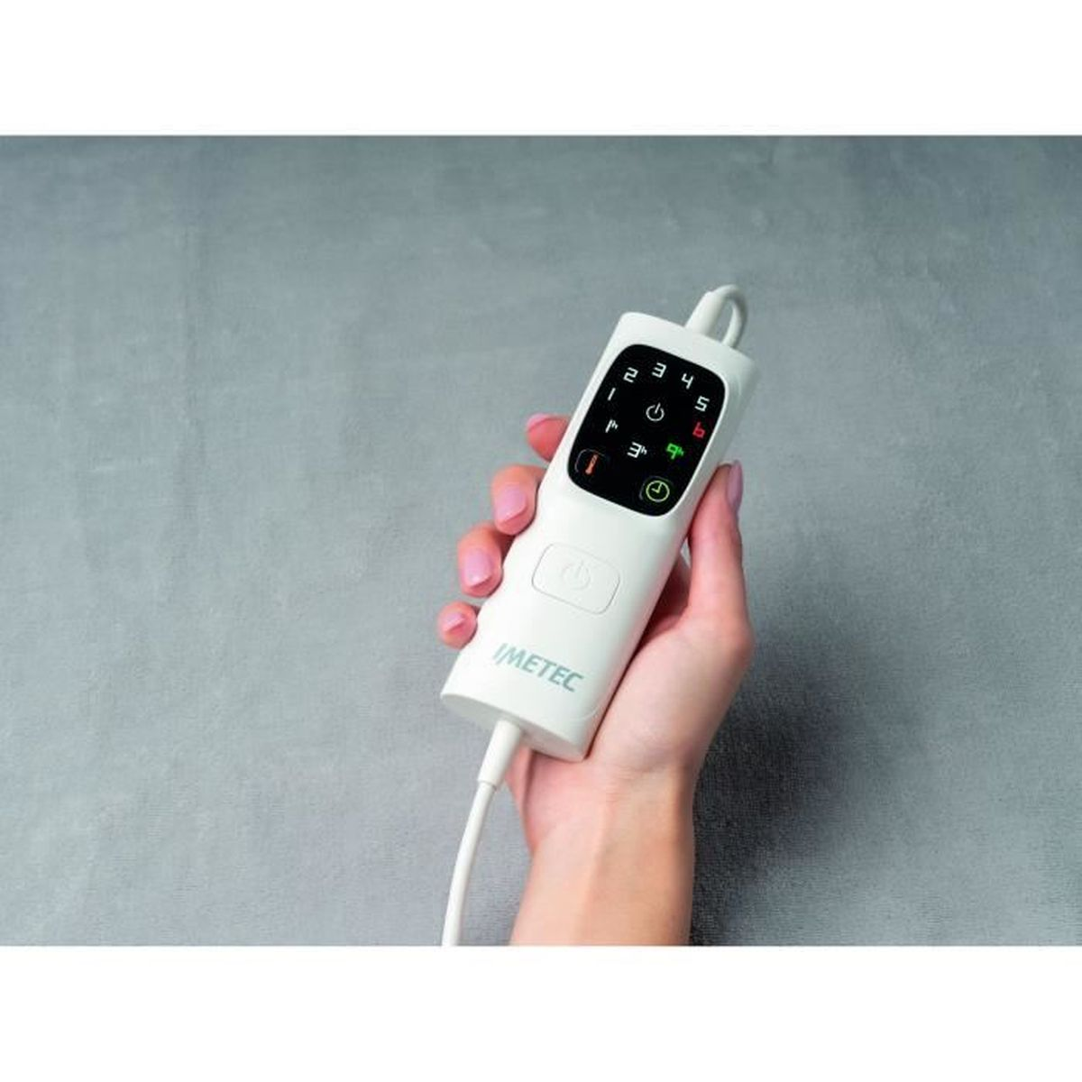 Mano che tiene un telecomando bianco con pulsanti e display. Il marchio Imetec è visibile.