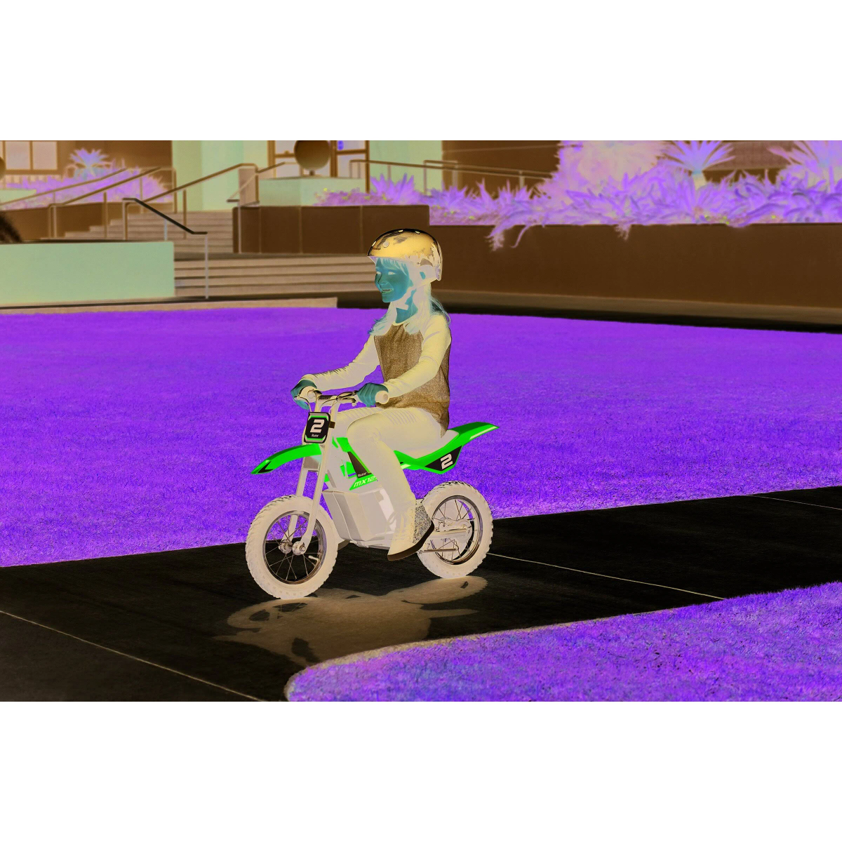 Invertiertes Bild eines Kindes auf einem kleinen grünen Motorrad, lila Hintergrund.
