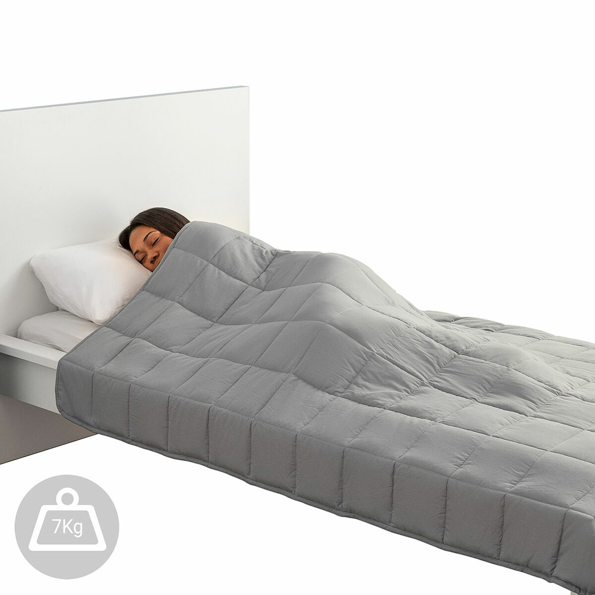 Una donna dorme sotto una coperta grigia ponderata sul letto. Un'etichetta del peso è visibile. Sfondo bianco.
