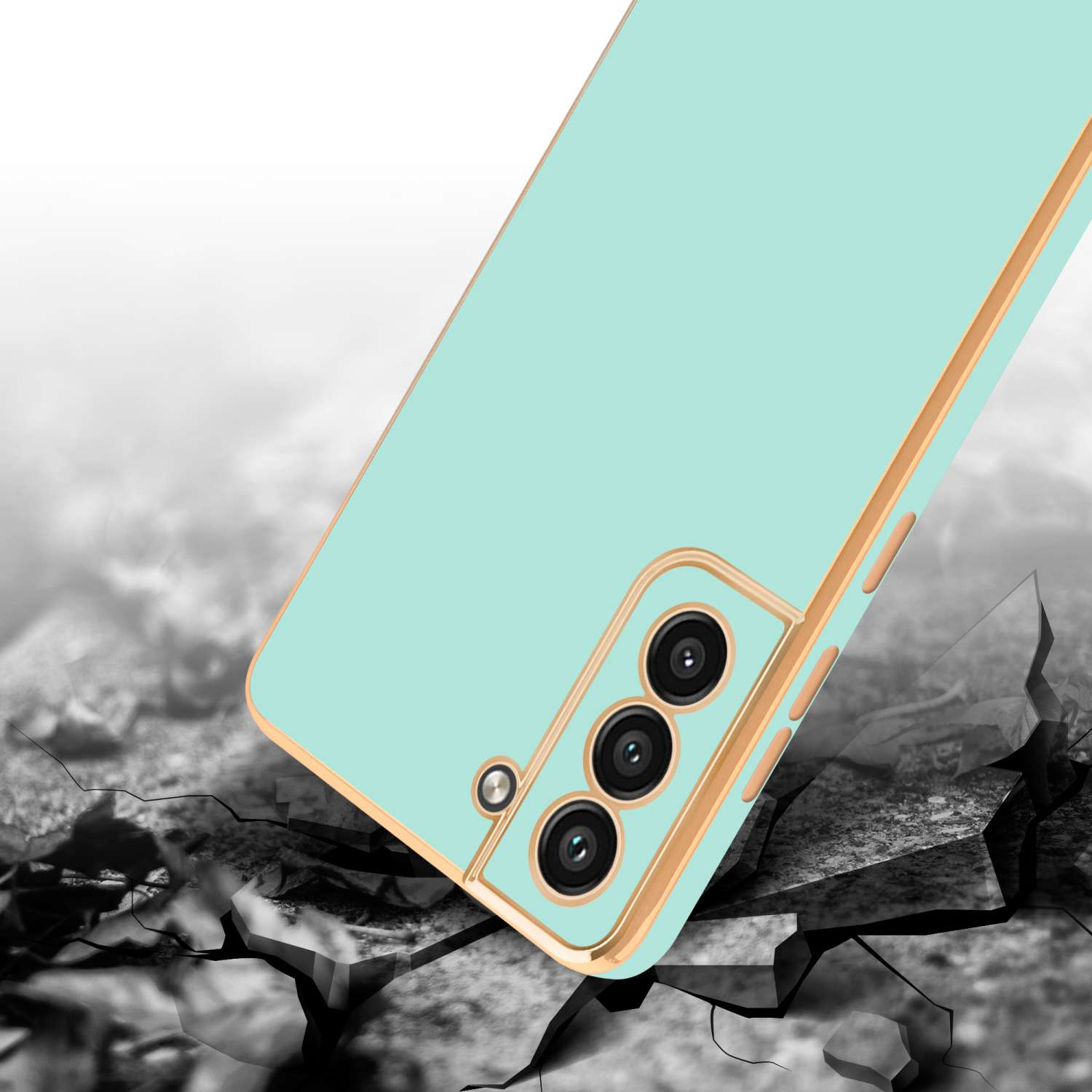 Una custodia per telefono verde menta con un bordo dorato è inclinata su una superficie incrinata. Sono visibili tre obiettivi della fotocamera.