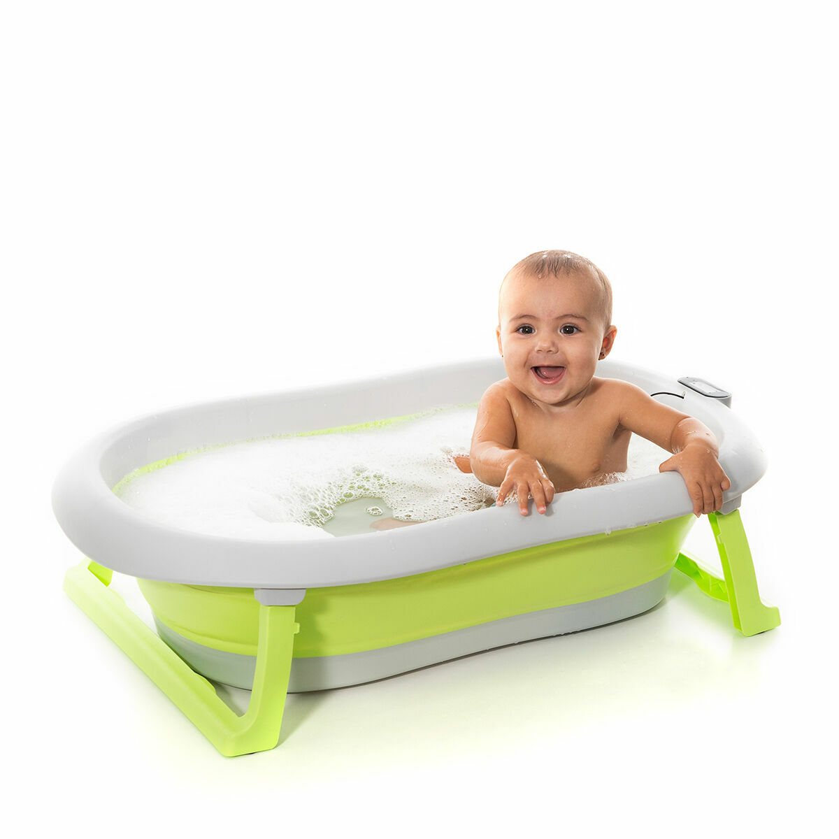 Baby in einer grün-weißen Babybadewanne, lächelnd. Weißer Hintergrund.