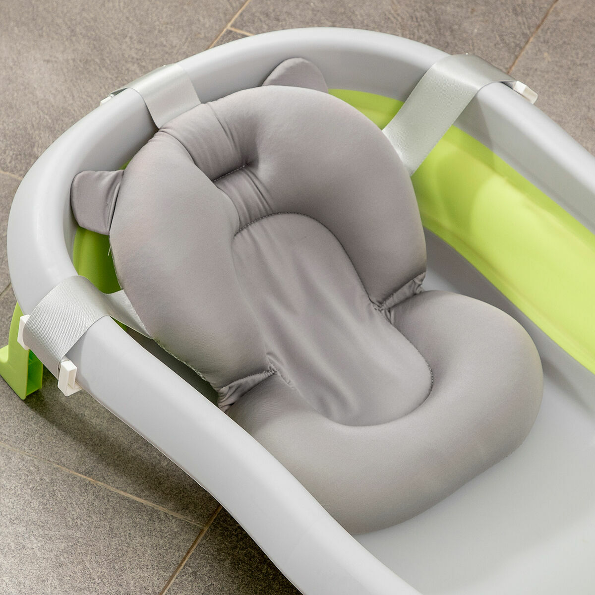 Graue Babybadewanne mit grauem Babybadewannenkissen. Die Wanne befindet sich in einem Badezimmer.