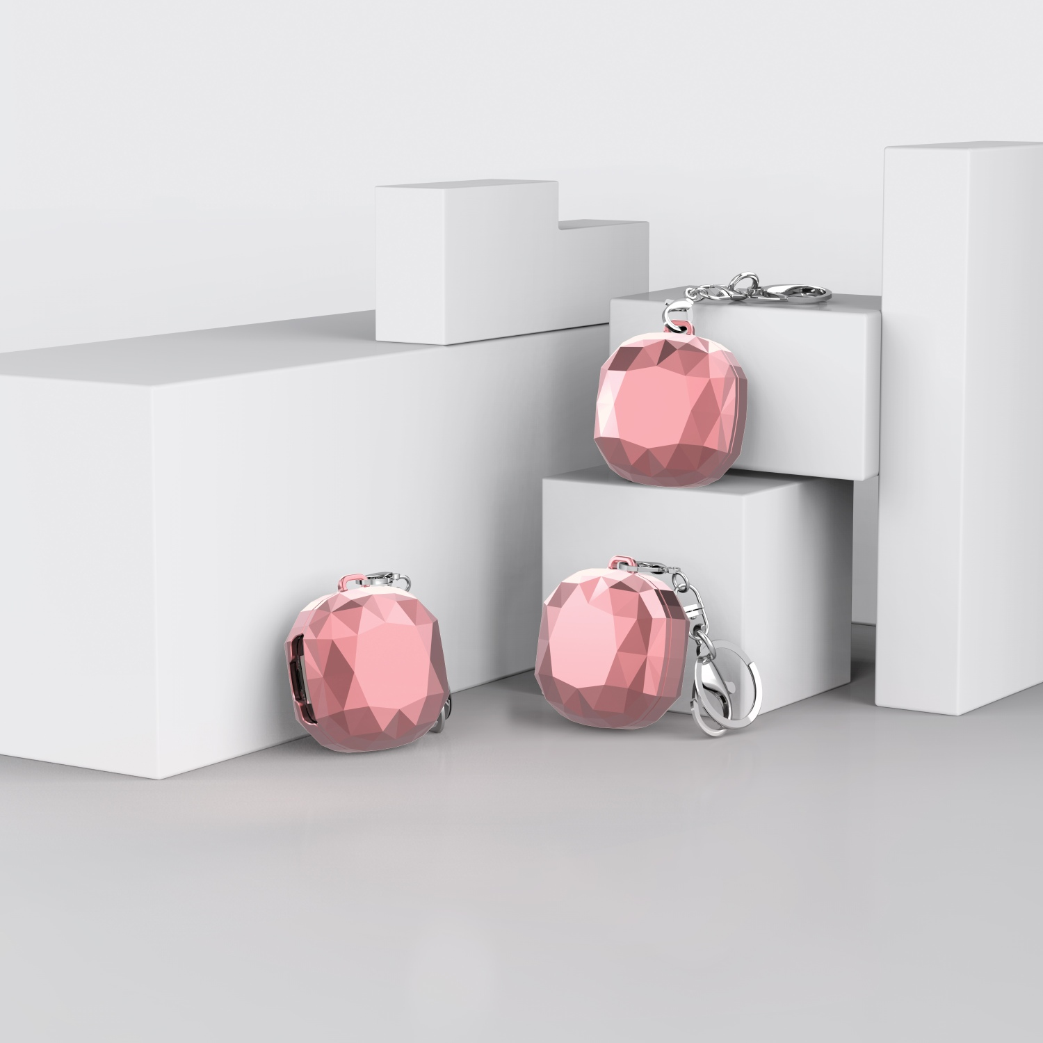 Drei rosa, geometrische, edelsteinartige Hüllen mit Schlüsselanhängern auf weißen Plattformen.