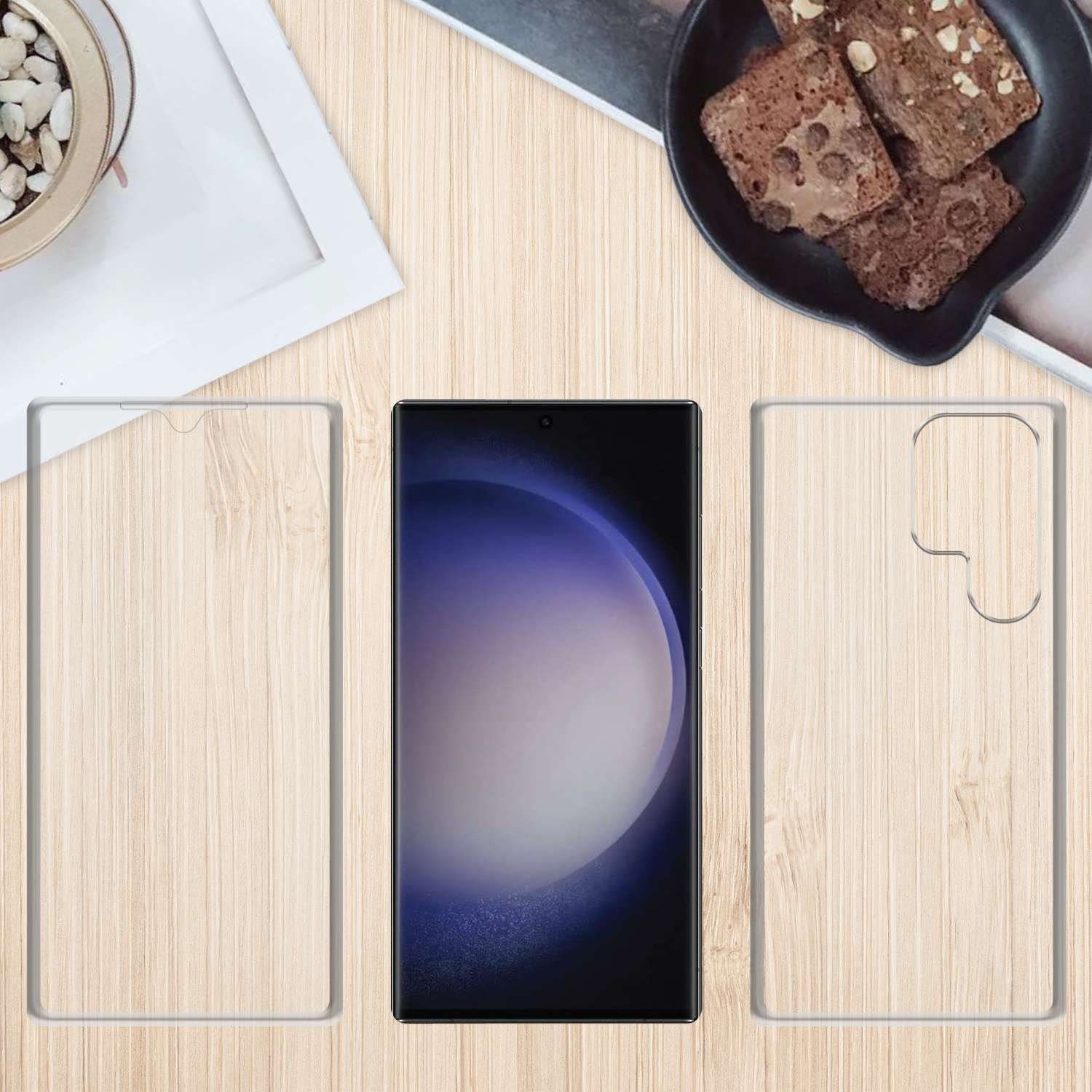Un telefono, una protezione per lo schermo e una custodia su un tavolo di legno con snack.