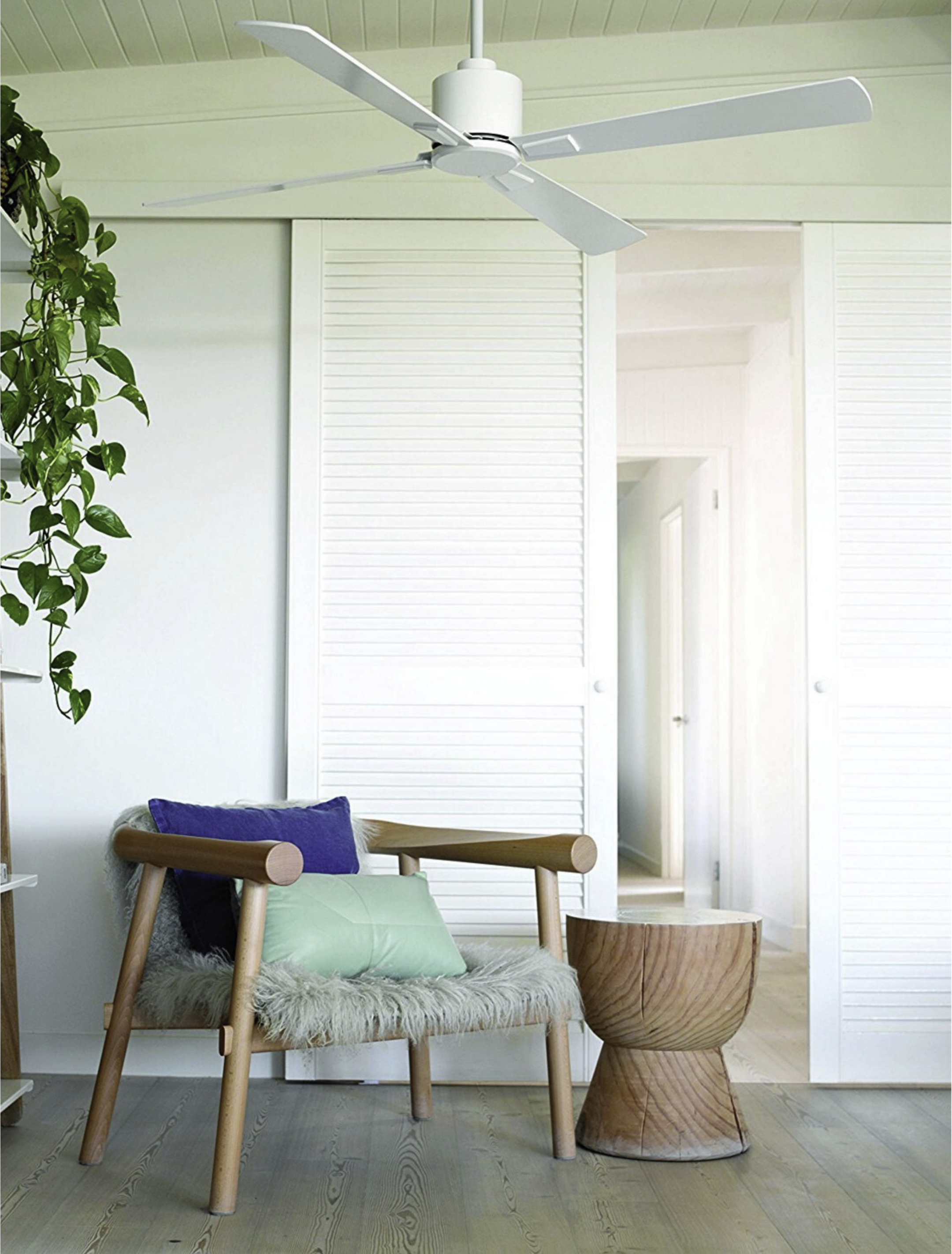 Ein Raum mit Deckenventilator und Stuhl mit Kissen. Der Raum hat weiße Türen.
