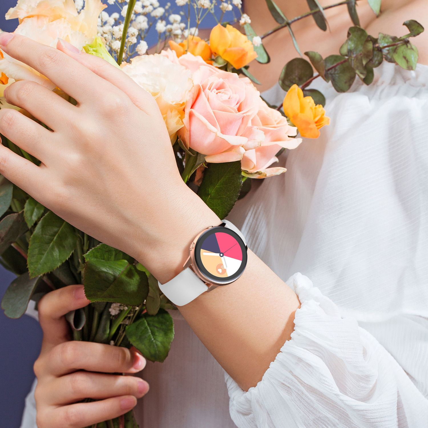 Arm einer Frau mit Uhr und Blumenstrauß. Die Uhr hat ein weißes Band und ein farbenfrohes Zifferblatt.