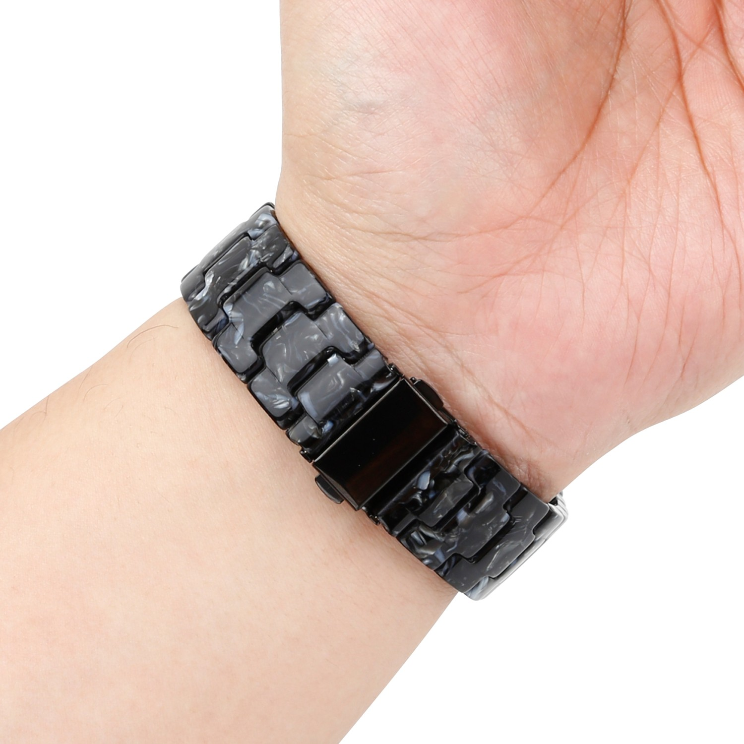 Handgelenk mit schwarz-weiß marmoriertem Uhrenarmband, mit schwarzem Verschluss.