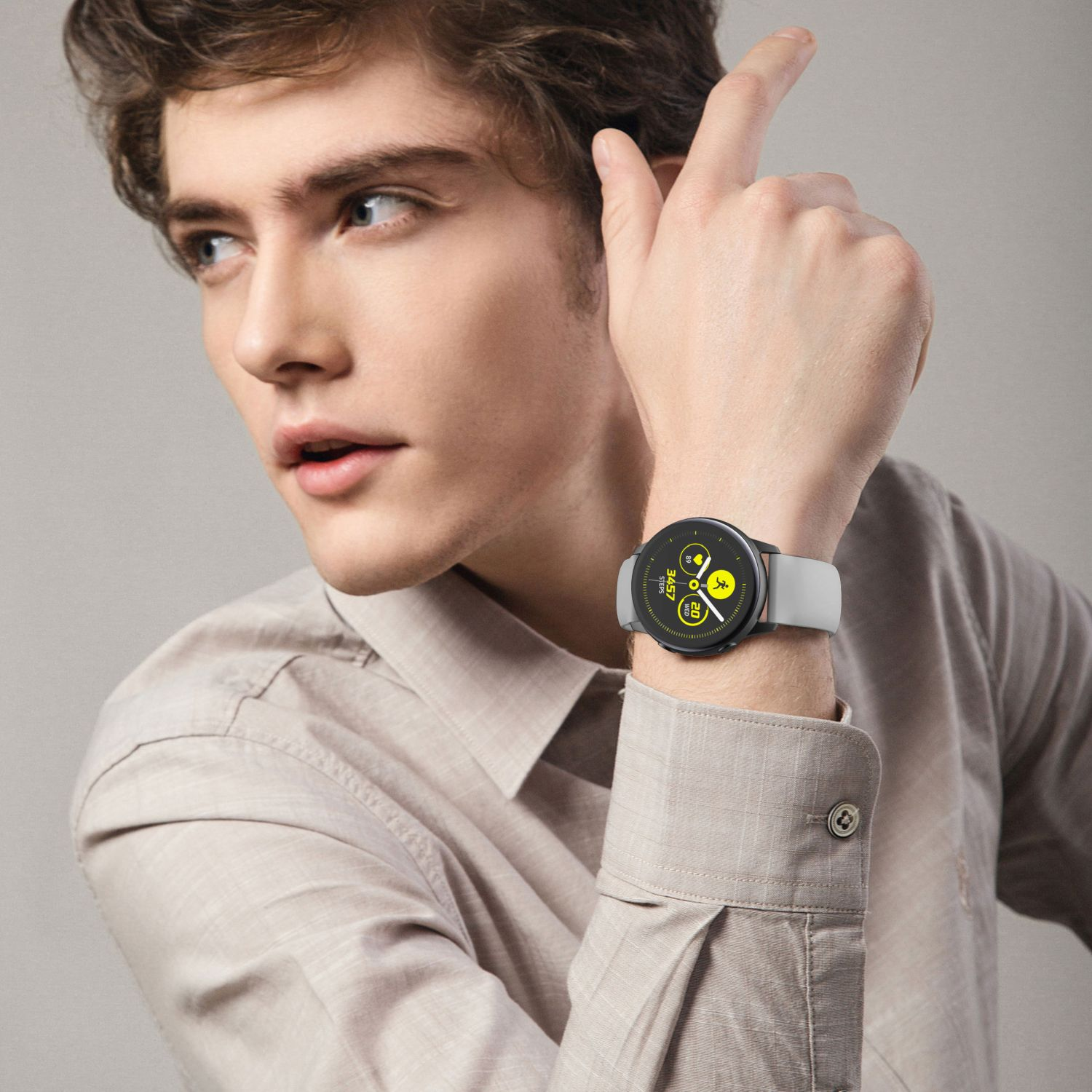 Mann mit Smartwatch mit grauem Armband. Das Zifferblatt zeigt Zeit, ein Sonnensymbol und Aktivitätsstatistiken.