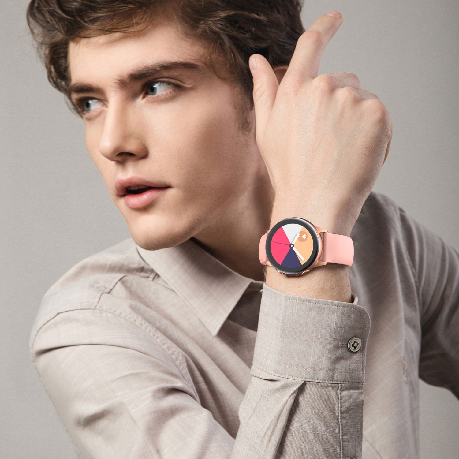 Ein Mann mit einer rosafarbenen Uhr. Die Uhr hat ein rundes Zifferblatt mit mehreren Farben, er zeigt mit dem Finger.