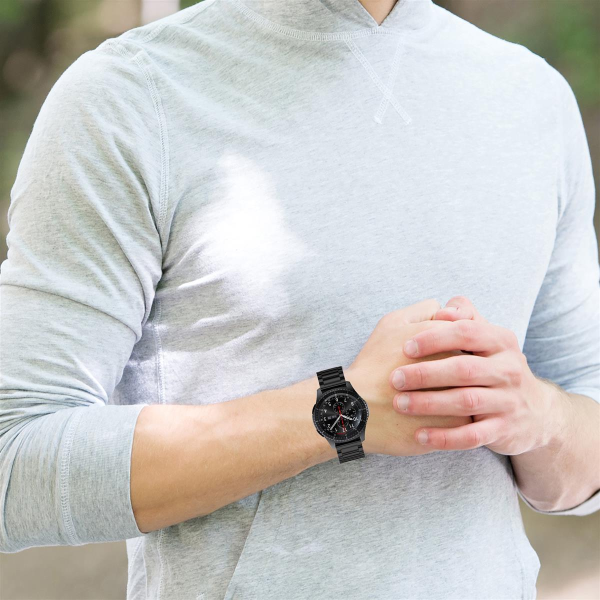 Eine Person trägt einen grauen Kapuzenpullover und eine schwarze Uhr am Handgelenk.