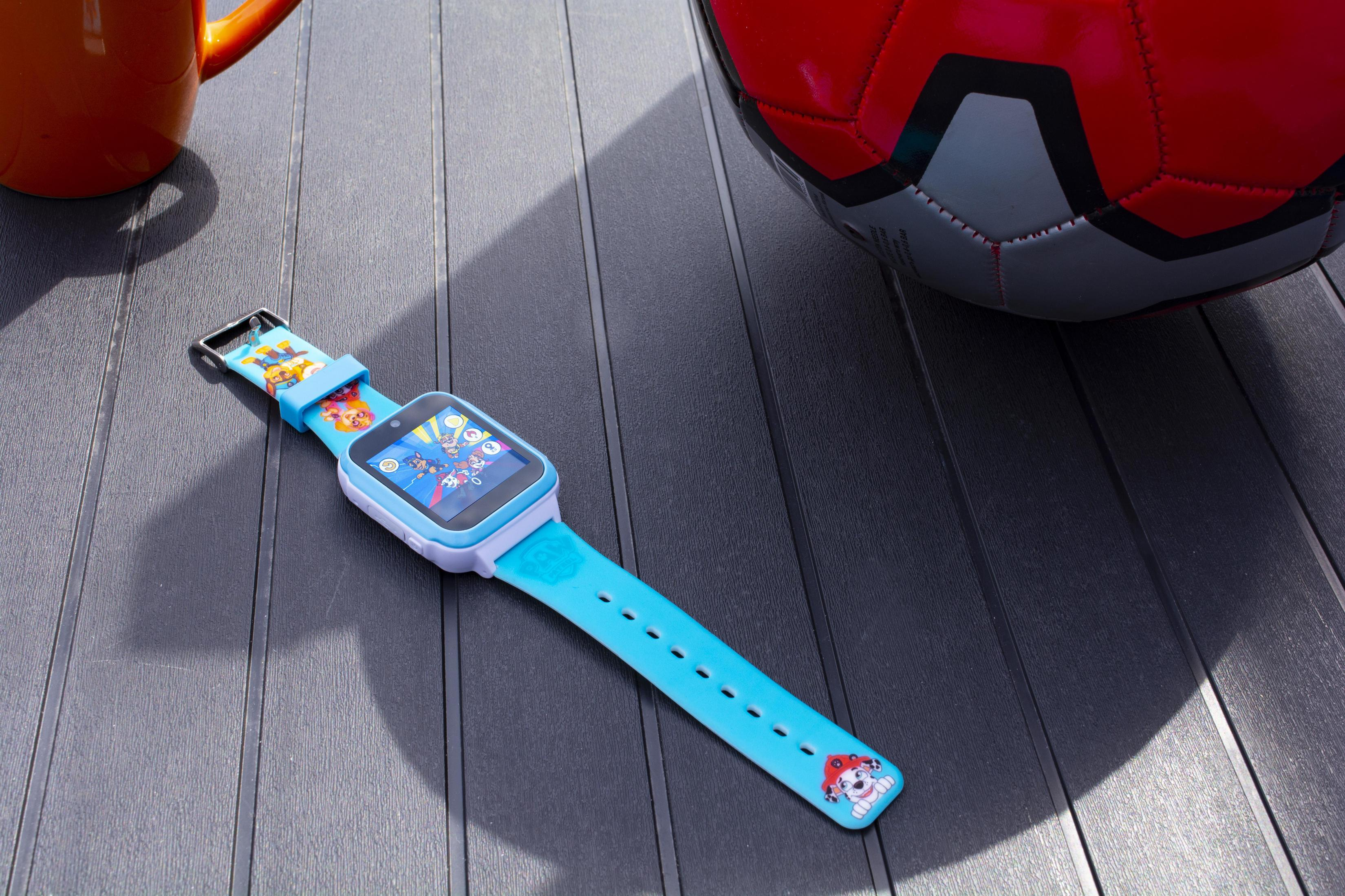 Uno smartwatch per bambini con un pallone da calcio e una tazza arancione su una superficie.