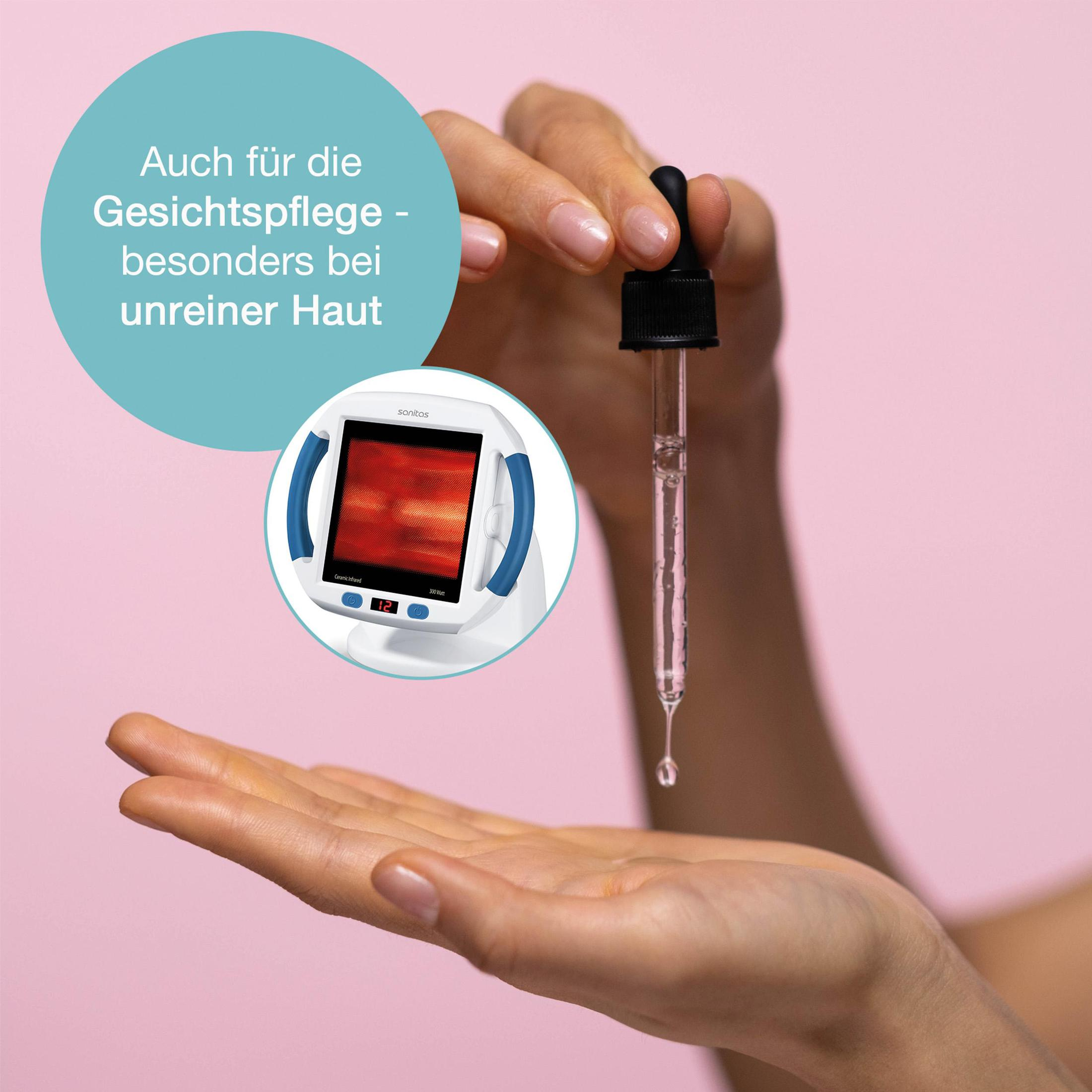 Mano di donna che tiene una pipetta con liquido. Un dispositivo per la terapia della luce rossa è sullo sfondo.