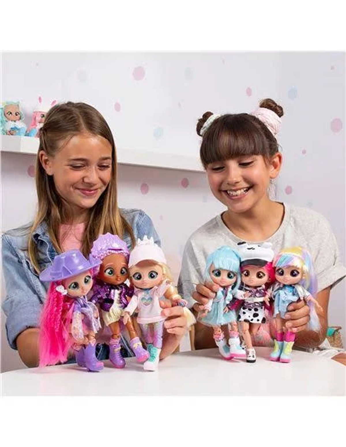 Zwei Mädchen halten Puppen. Die Puppen haben bunte Kleidung und unterschiedliche Frisuren.