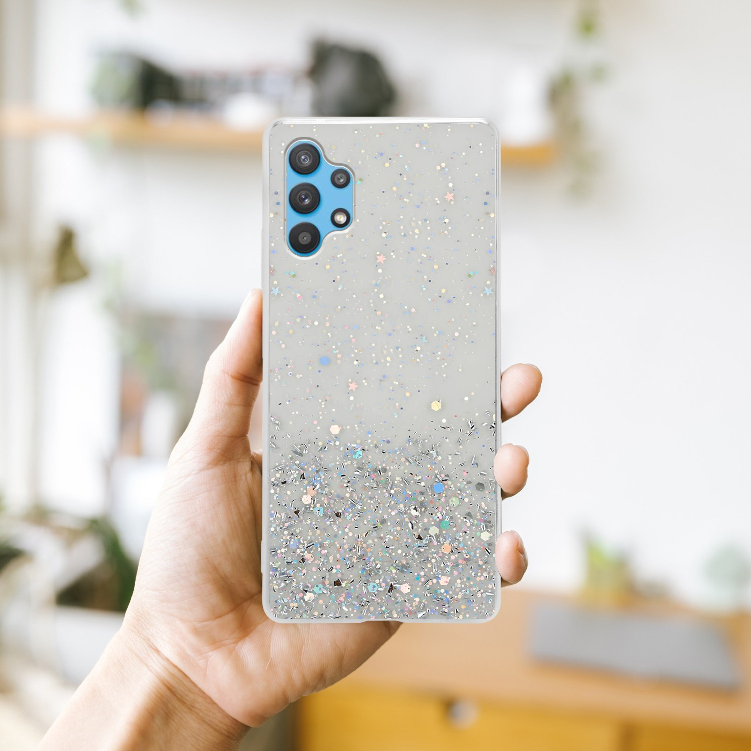 Una mano che tiene una custodia per telefono con un design glitterato. Lo sfondo è sfocato.