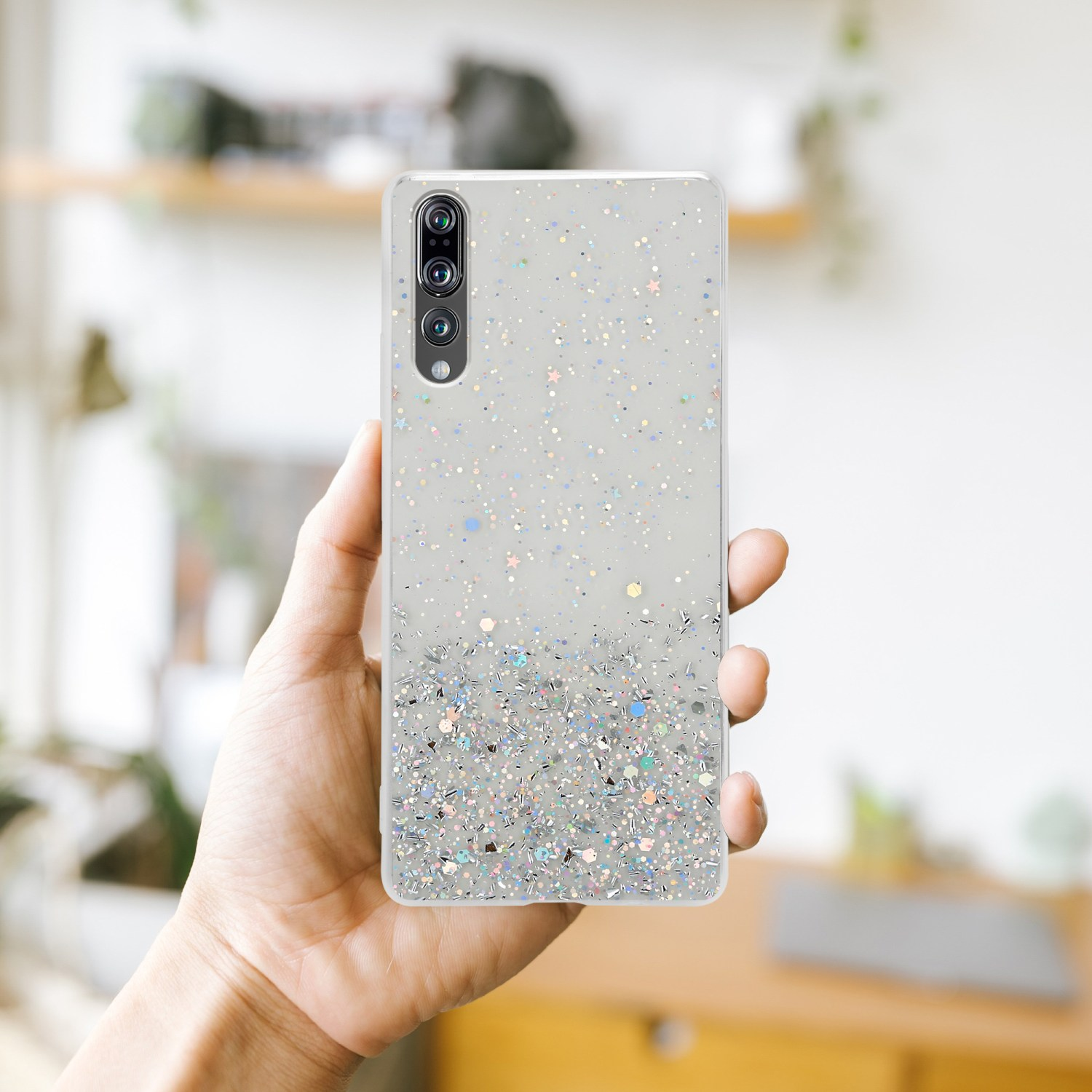 Una mano tiene una custodia per telefono con glitter.
