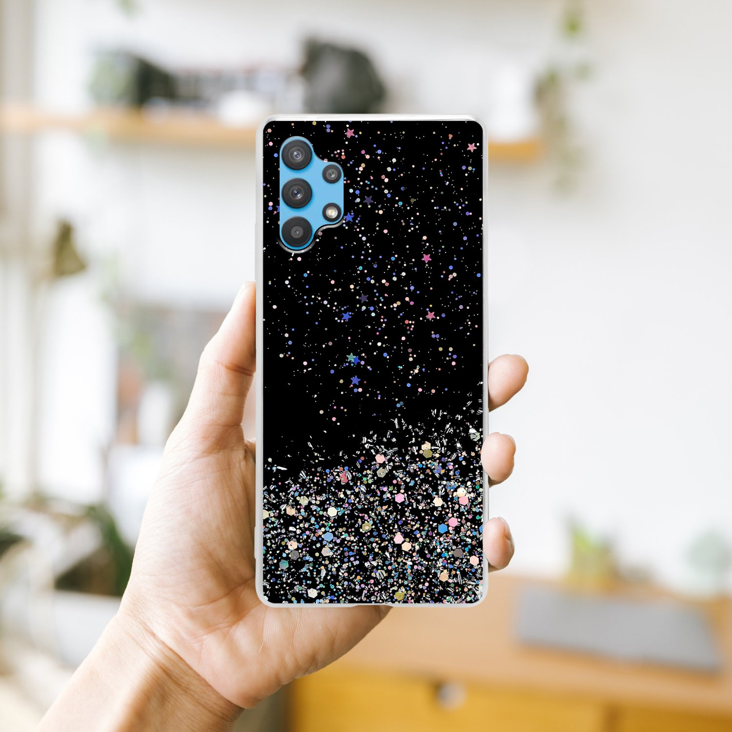 Una mano che tiene una custodia per telefono nera con un design glitterato nero con glitter colorati.